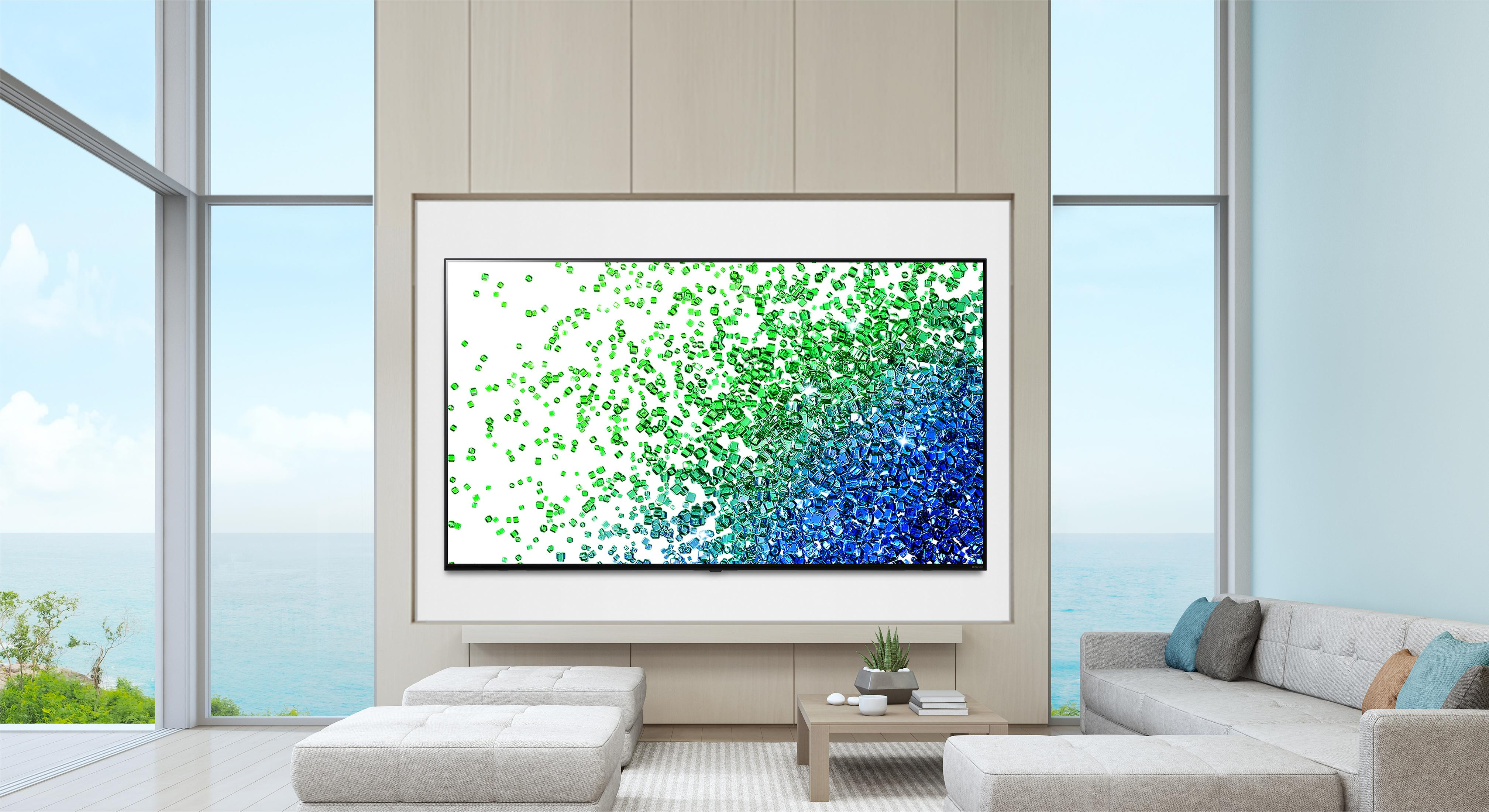 Una sala de estar moderna con vista al mar, TV grande muestra cristales coloridos.