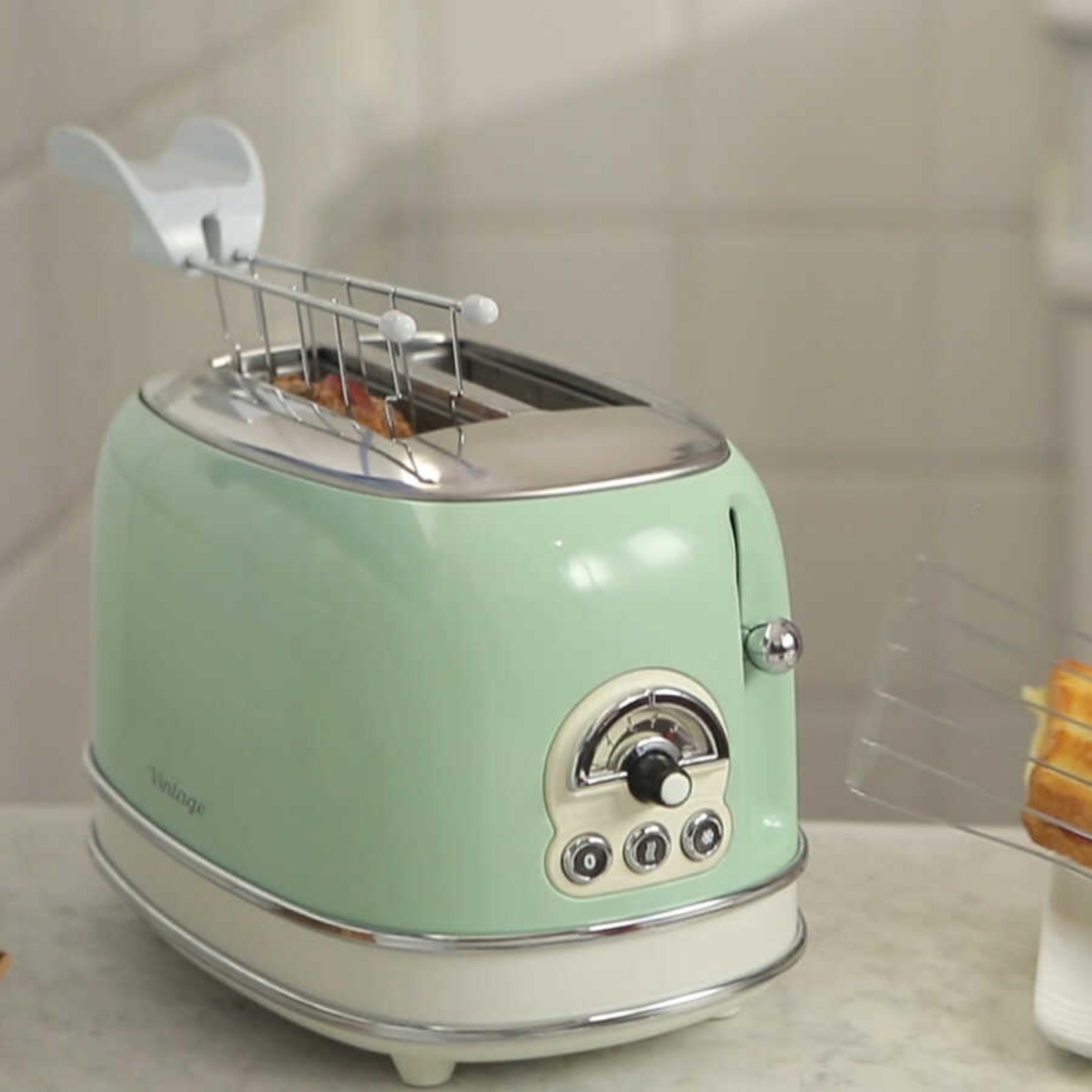 A mint green vintage toaster with chrome details and toast in the slot.