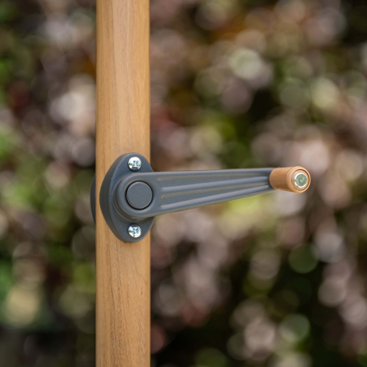 Grijze slinger met houten handvat aan bruine paal, wazige buitenachtergrond.