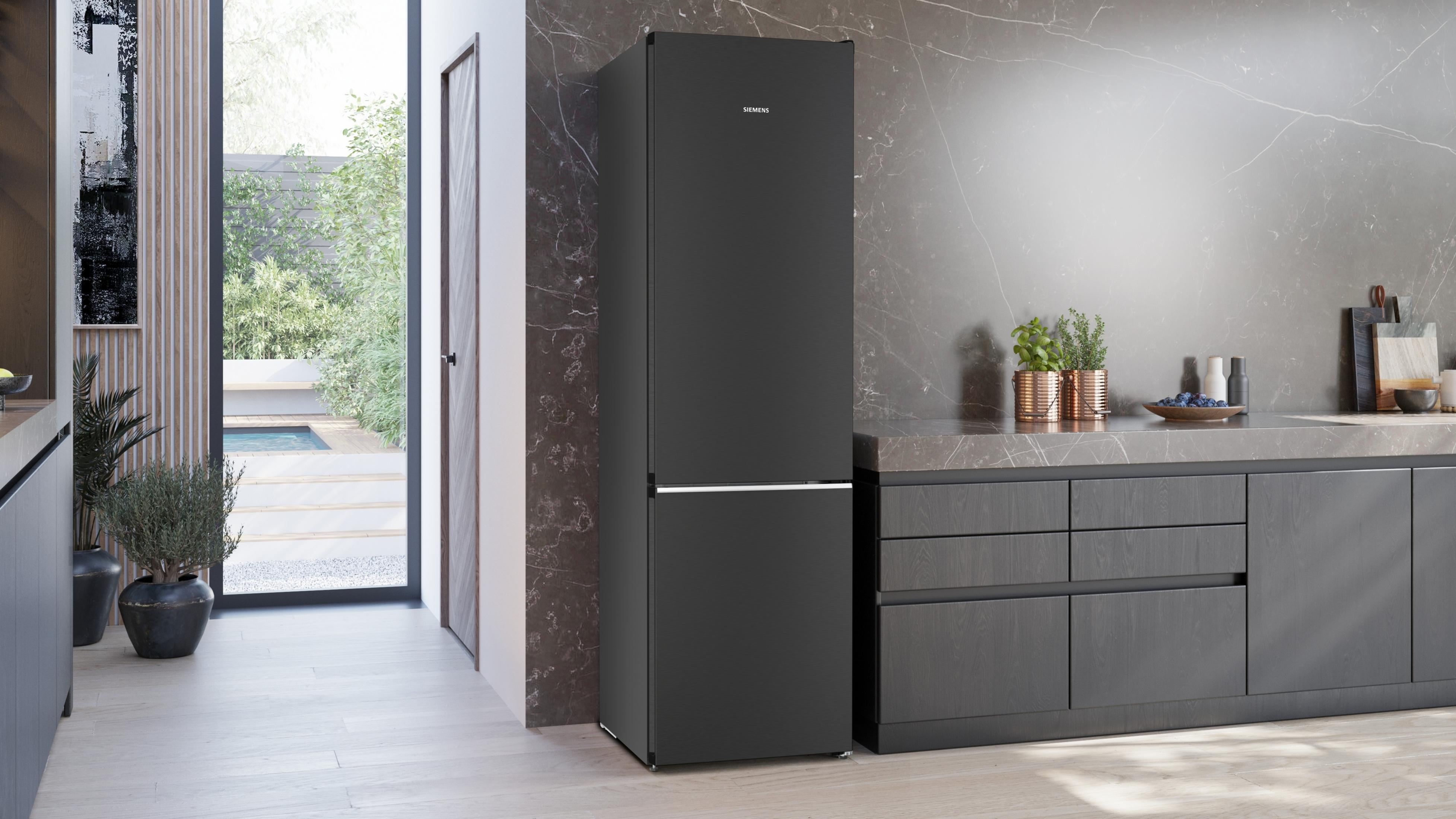 Ein schwarzer Siemens-Kühlschrank steht in einer modernen Küche neben dunklen Schränken.
