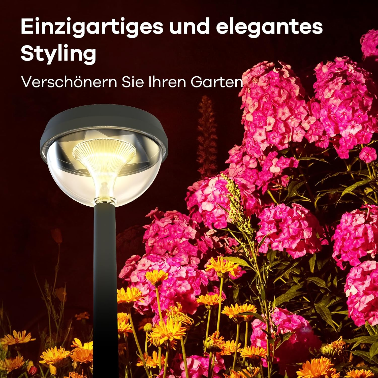 Eine moderne Gartenleuchte beleuchtet bunte Blumen bei Nacht.