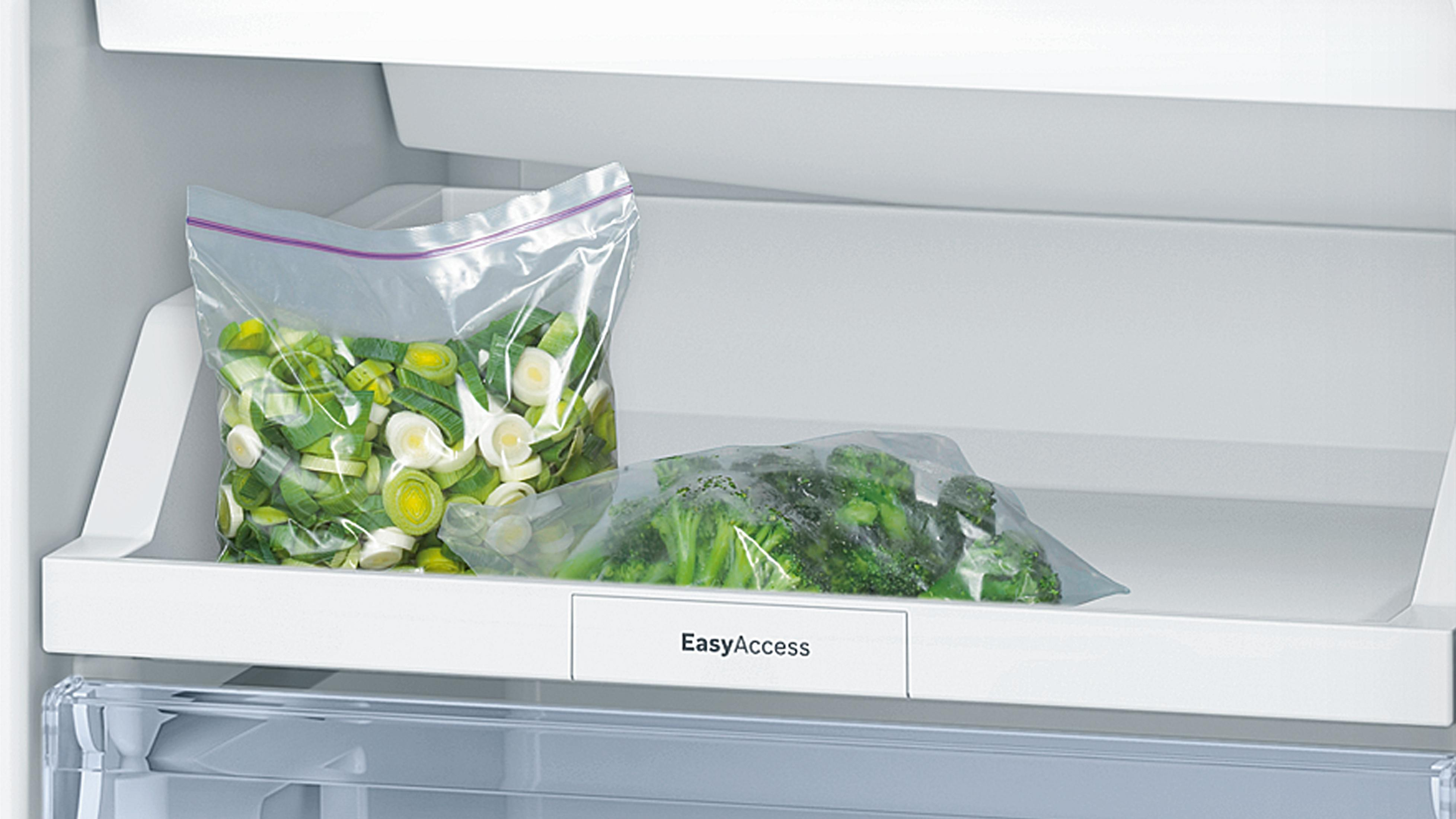 Dwa plastikowe worki z pokrojonym porem i brokułami na półce lodówki. Etykieta EasyAccess.