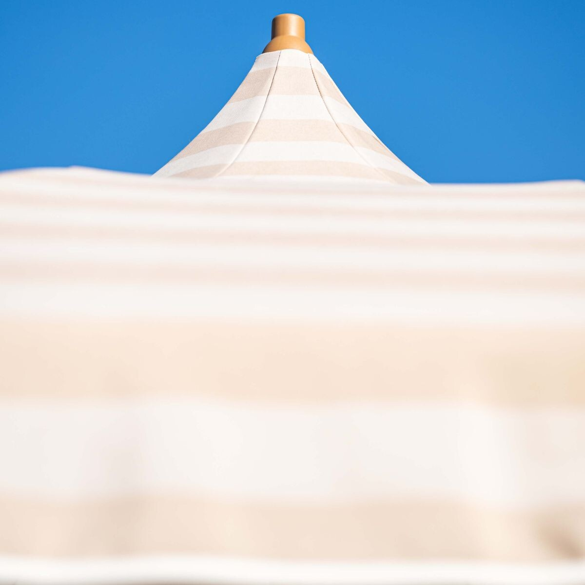 Een gestreepte parasol tegen een blauwe lucht.