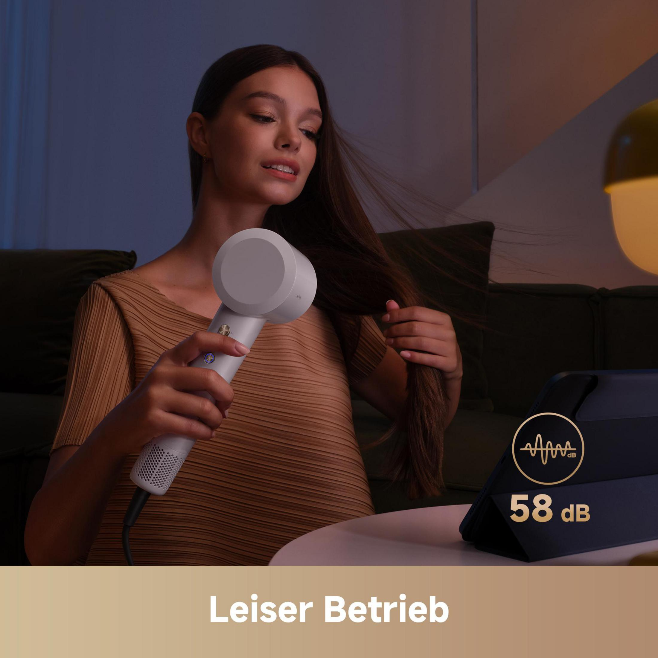 Mujer se seca el pelo con secador blanco. Tablet muestra 58 dB.