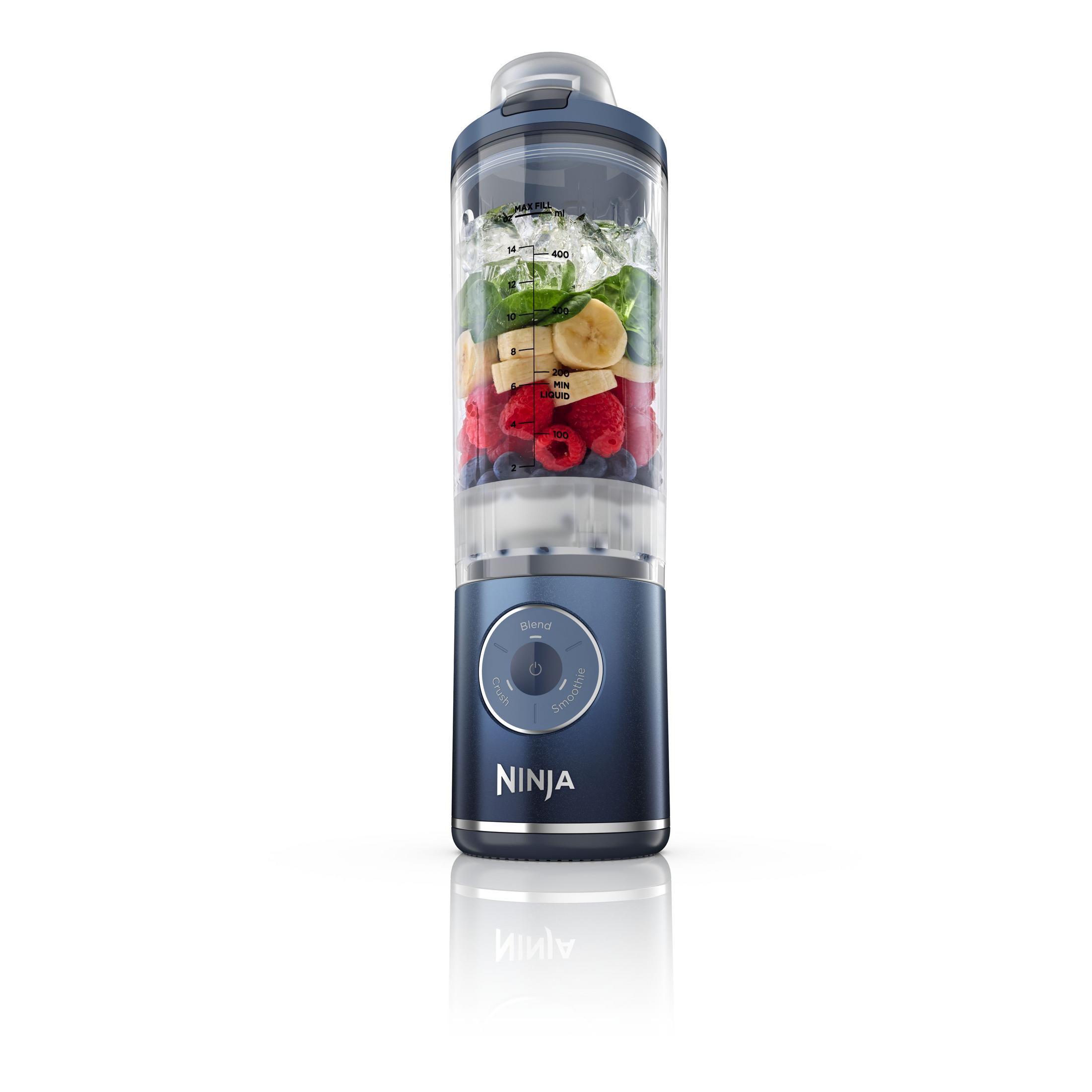 Un frullatore Ninja blu riempito con banane, frutti di bosco e spinaci.