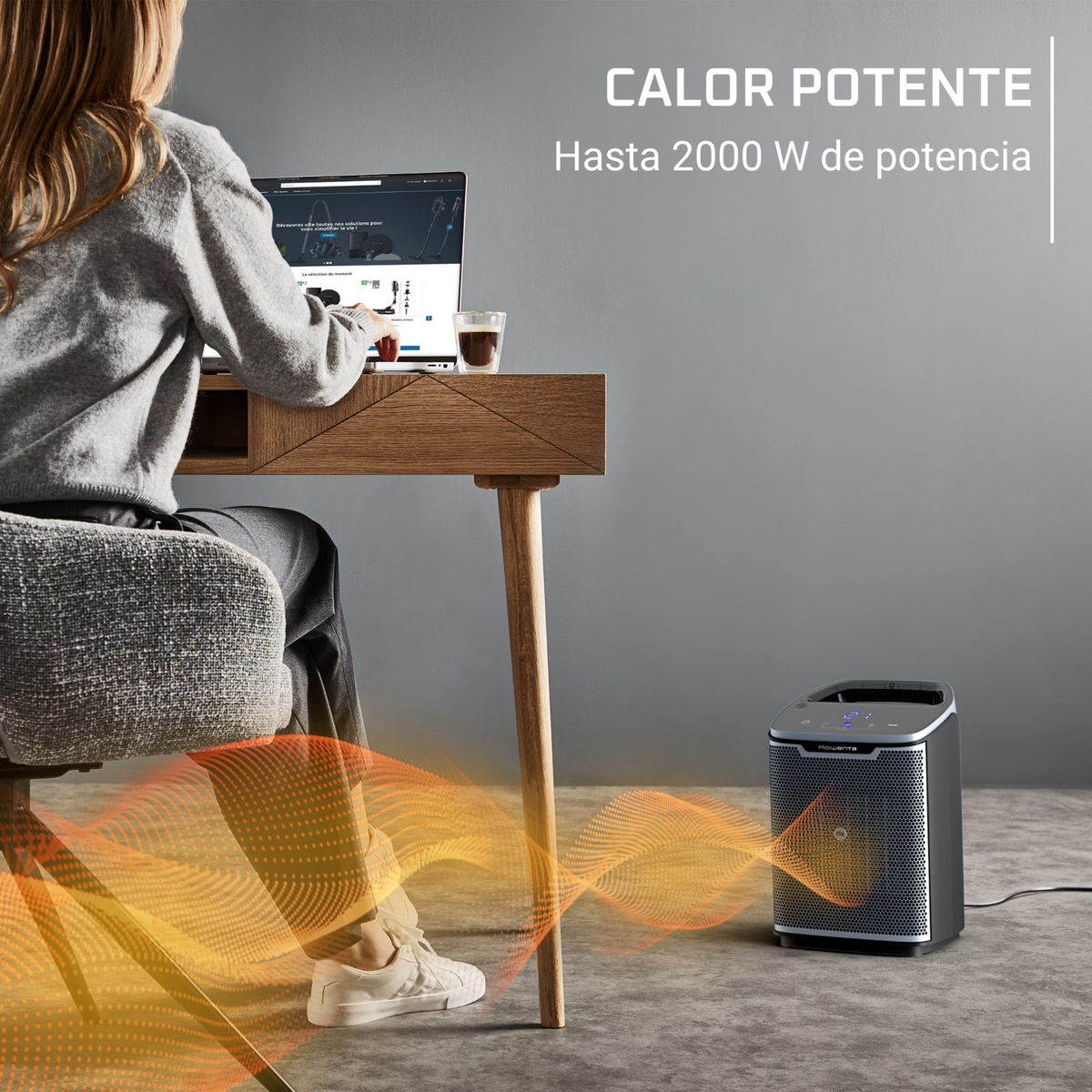 Osoba siedzi przy biurku, grzejnik ogrzewa obszar pod biurkiem.