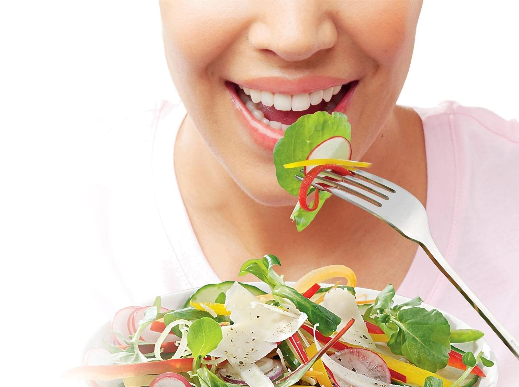 Woman eating salad with a fork, full of vegetables and cheese.