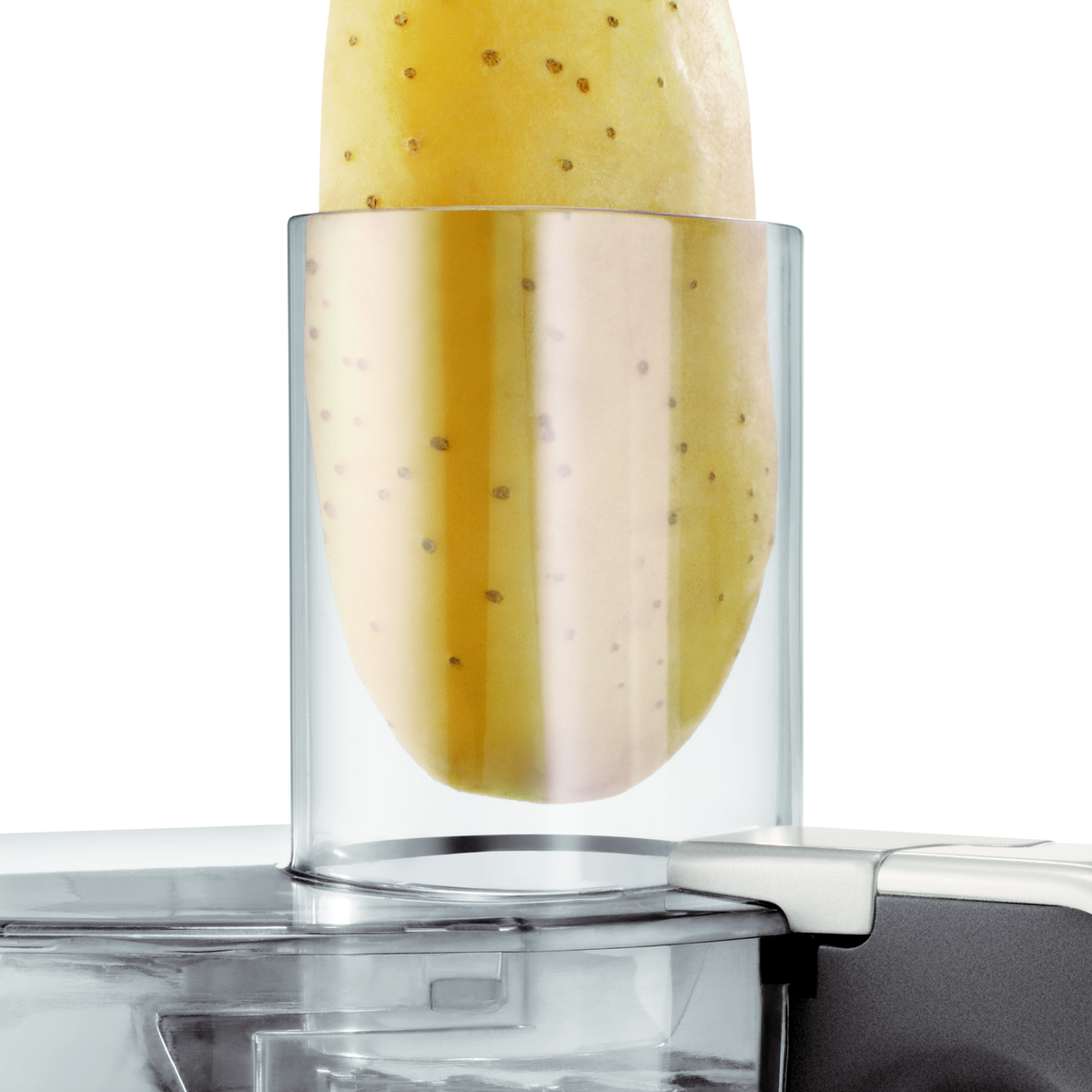 A potato is being processed in a glass container on a kitchen appliance.