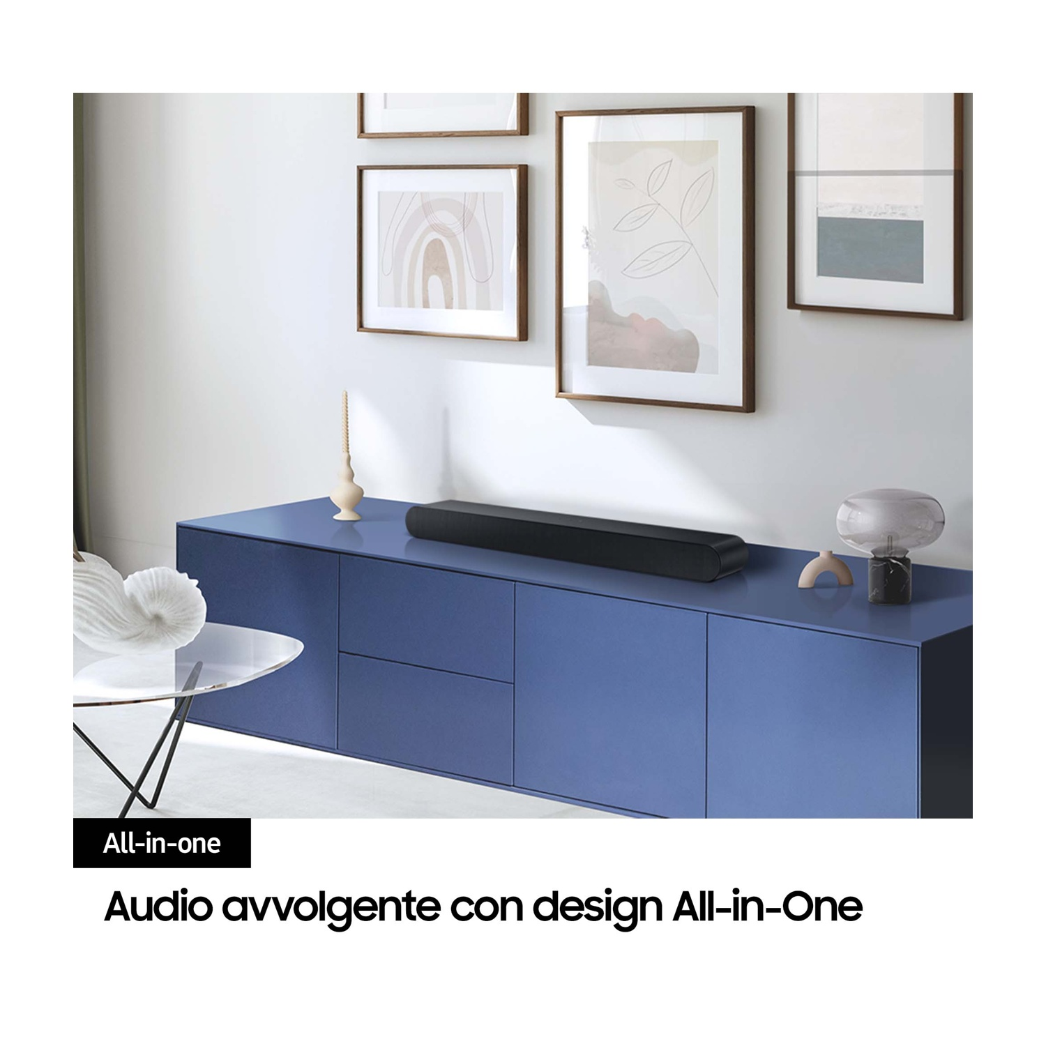 Czarny soundbar na niebieskim kredensie z oprawionymi obrazami na ścianie.