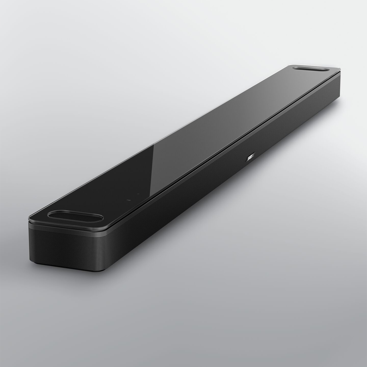 Schwarzer Bose Soundbar mit glänzender Oberfläche und perforierten Seiten auf grauem Hintergrund.