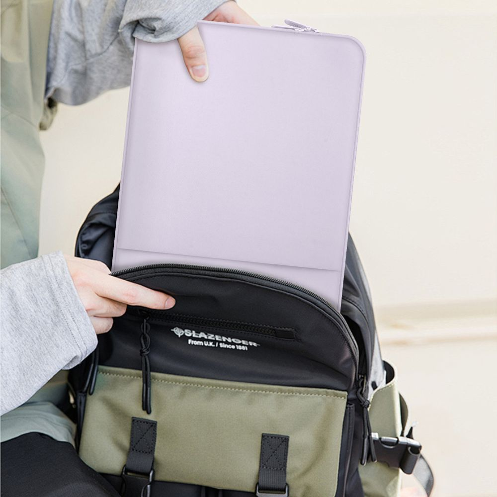 Eine Person packt eine hellviolette Hülle in einen Rucksack mit grünen und schwarzen Fächern.