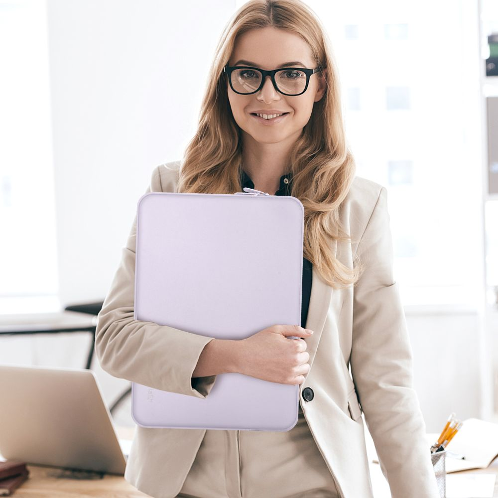 Eine Frau mit Brille hält eine lila Laptoptasche vor sich.