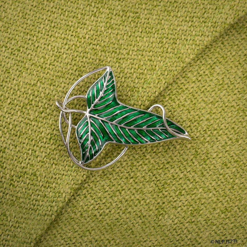 Grüne Brosche in Form eines Blattes auf grünem Strickstoff.