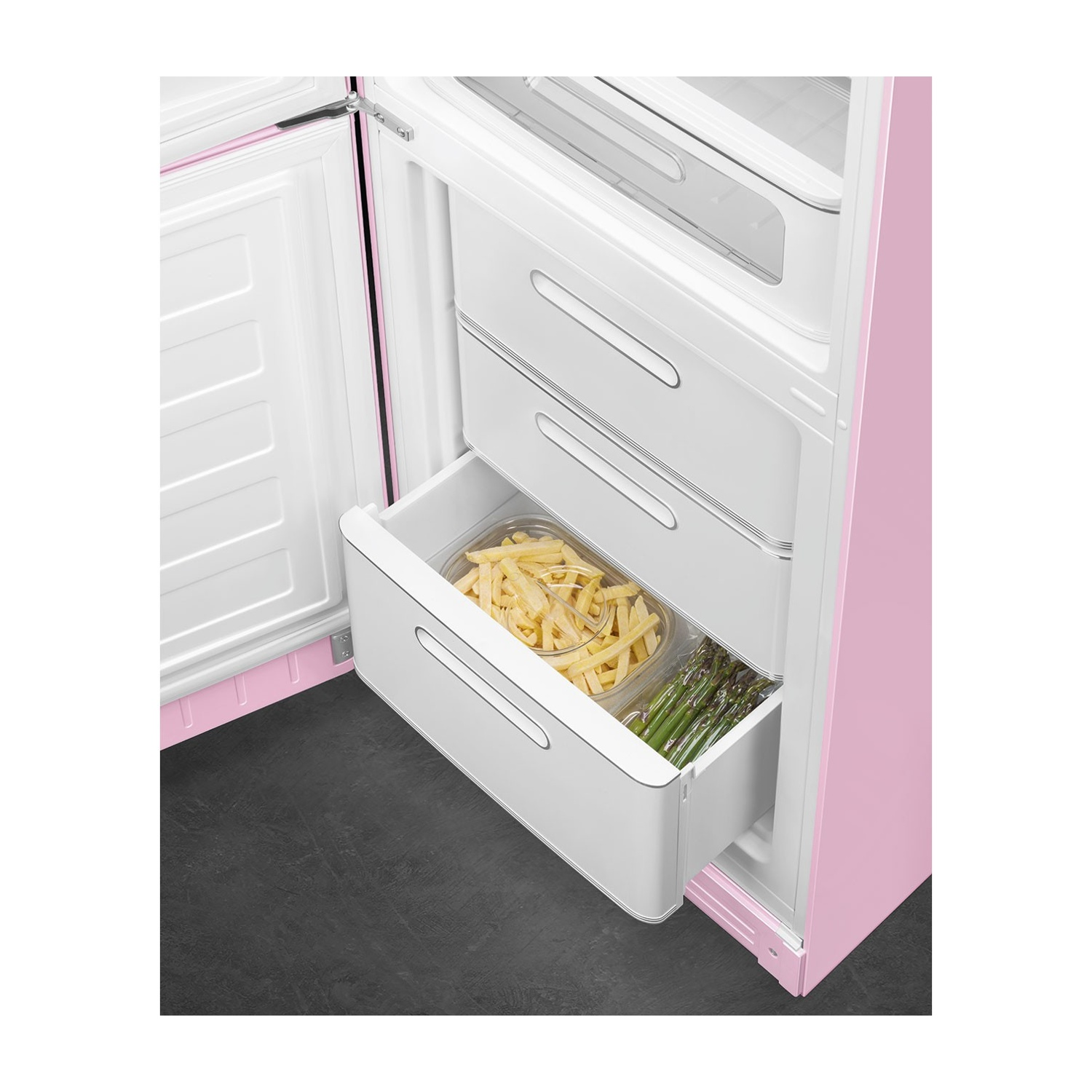 Refrigerador rosa con cajones abiertos que contienen papas fritas y espárragos.