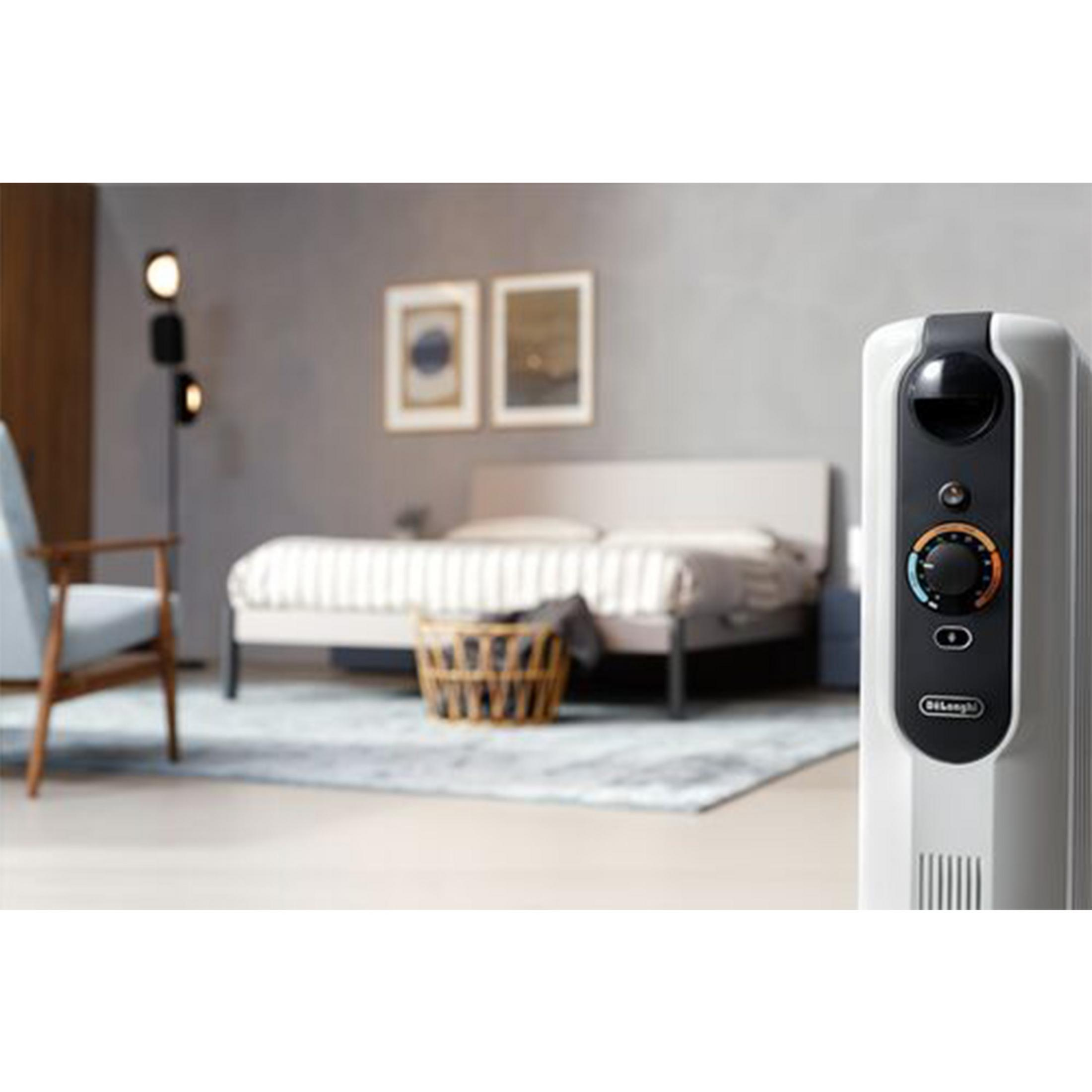 Biały grzejnik na pierwszym planie. W tle łóżko, fotel i obrazy.