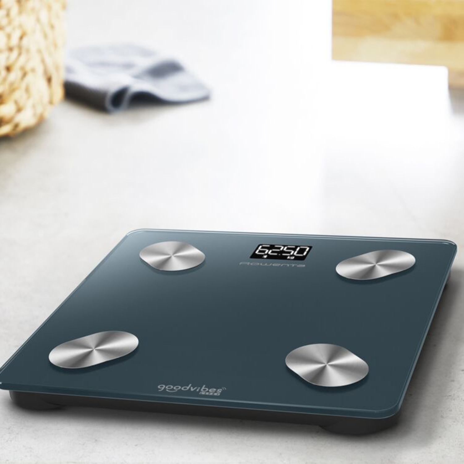 Ciemnoniebieska waga cyfrowa ze srebrnymi czujnikami. Wyświetlacz pokazuje 62,50 kg.