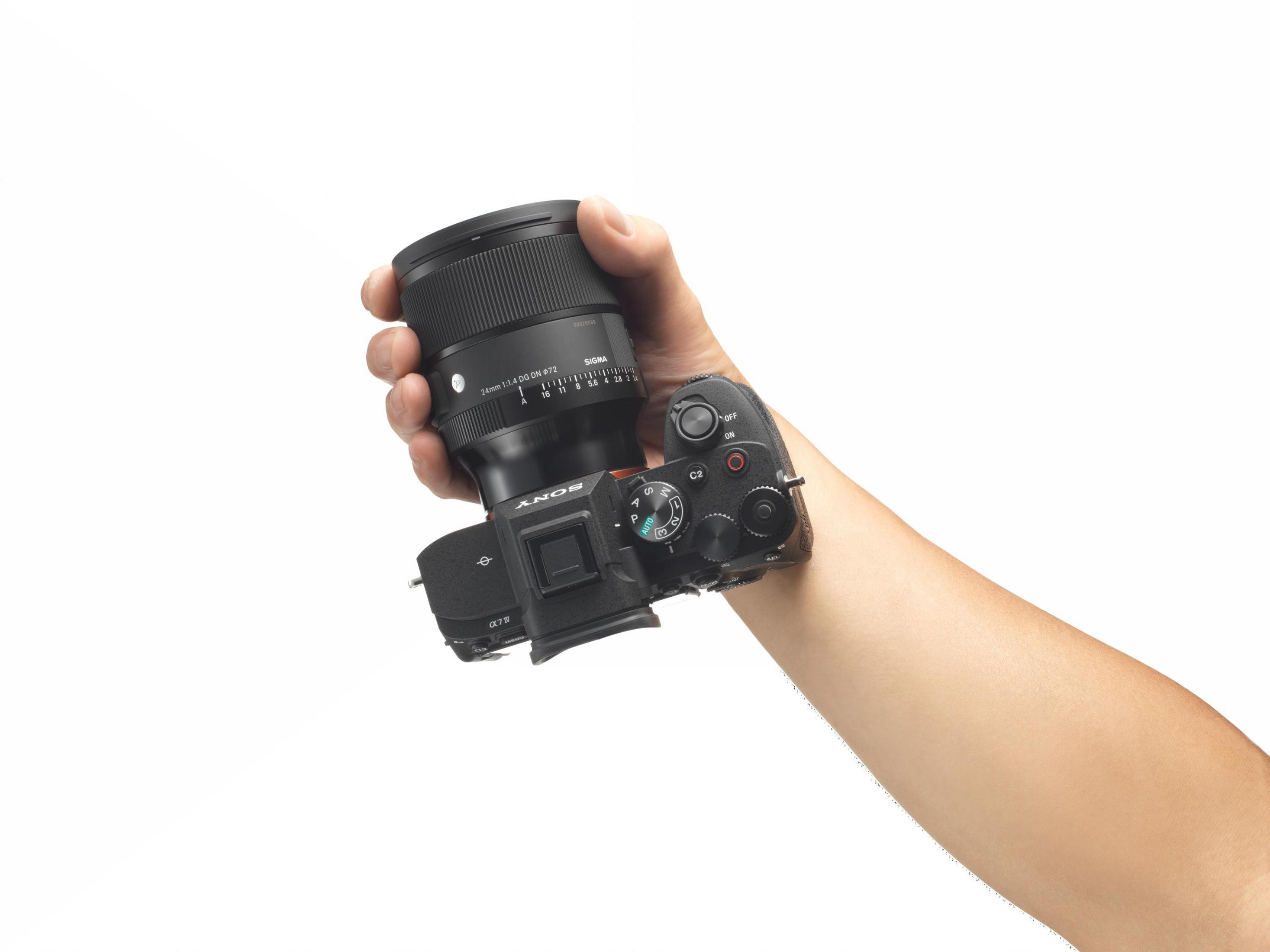 Dłoń trzyma aparat Sony Alpha 7 IV z obiektywem Sigma 24mm.
