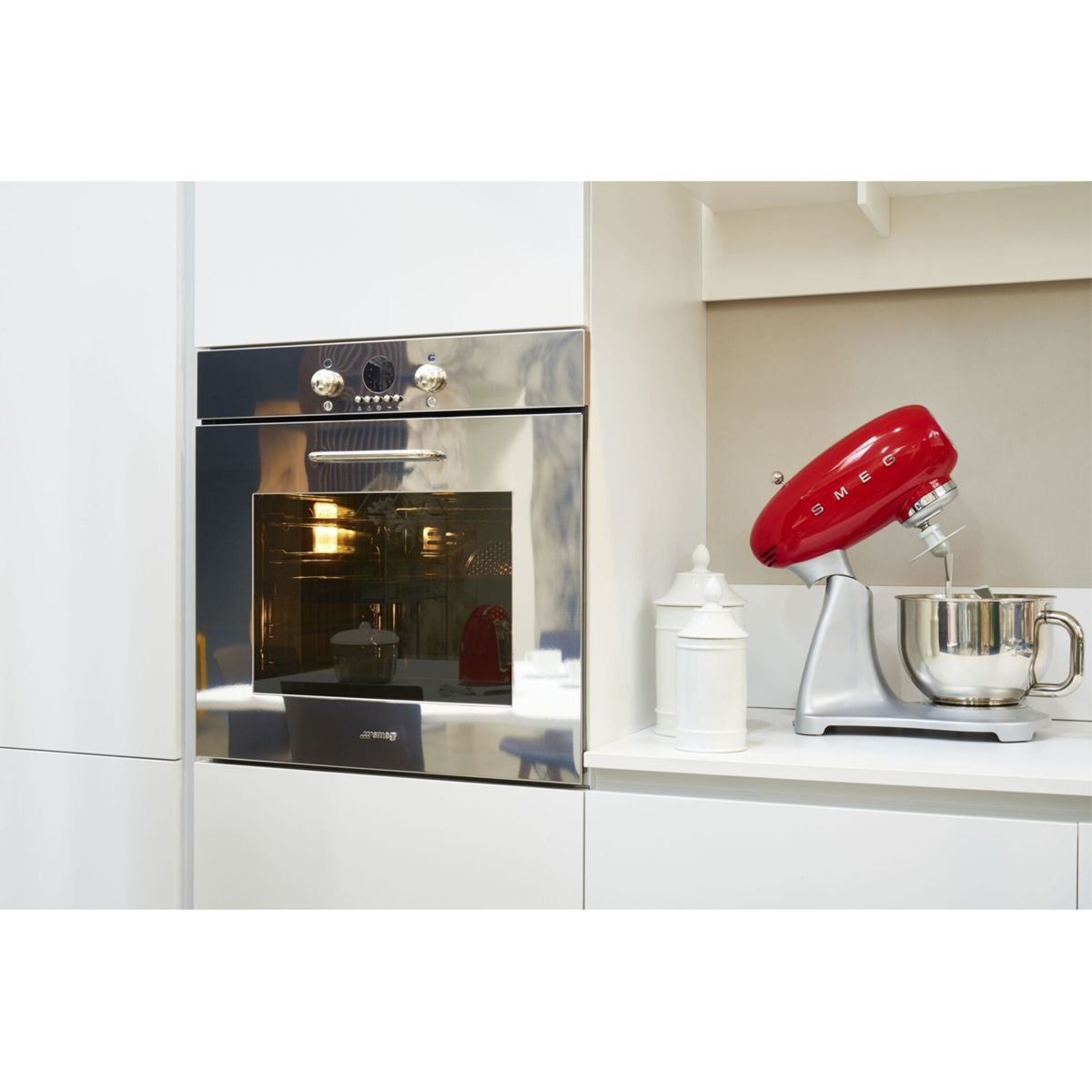 Parlak bir fırının yanında tezgahta kırmızı bir Smeg stand mikseri duruyor.