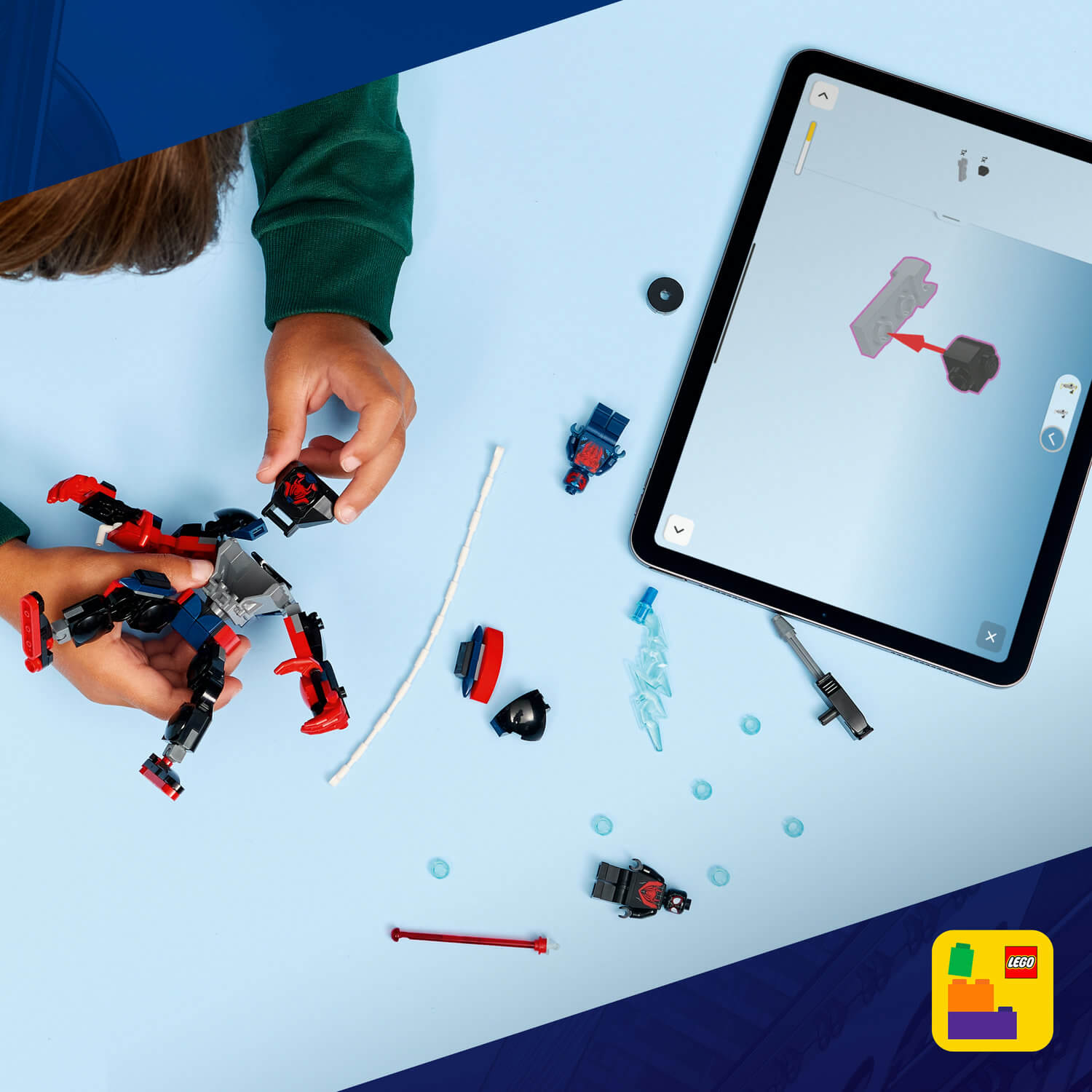 Niño construye figura Lego con instrucciones en tablet. Piezas esparcidas.