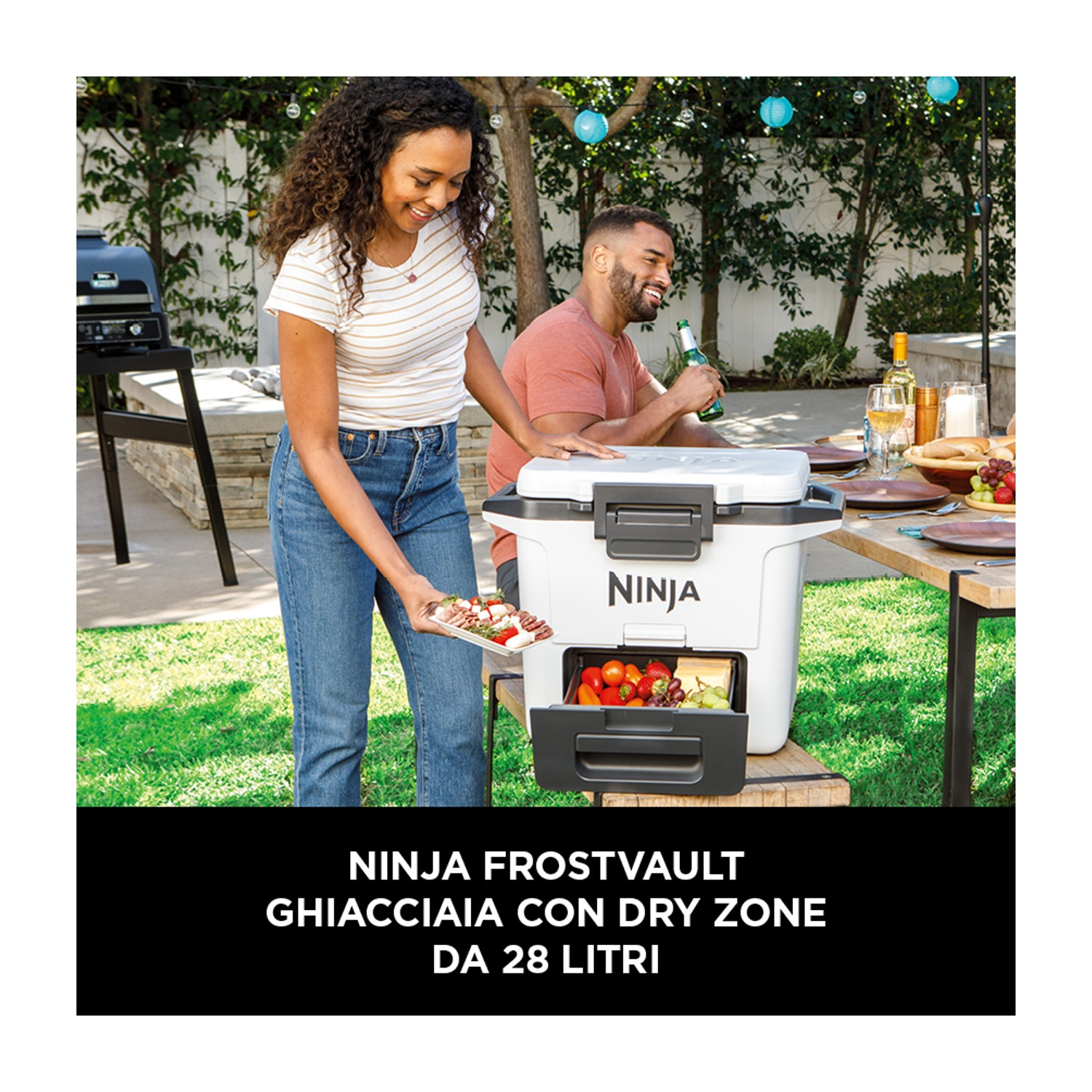 Mężczyzna i kobieta w ogrodzie przy stole z lodówką Ninja.
