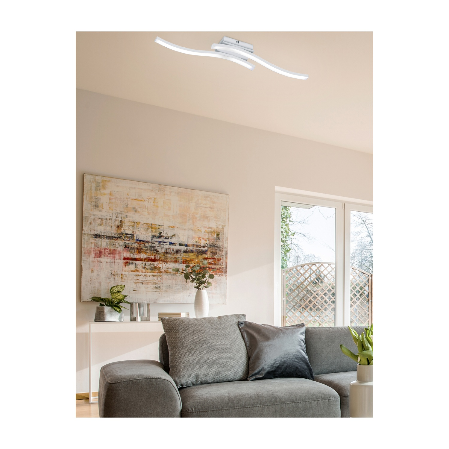Soggiorno moderno con divano grigio, arte e lampada da soffitto curva.