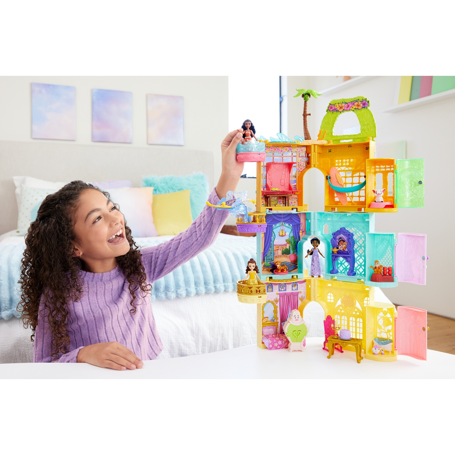 Una niña juega con un colorido castillo de casa de muñecas con figuras y muebles.