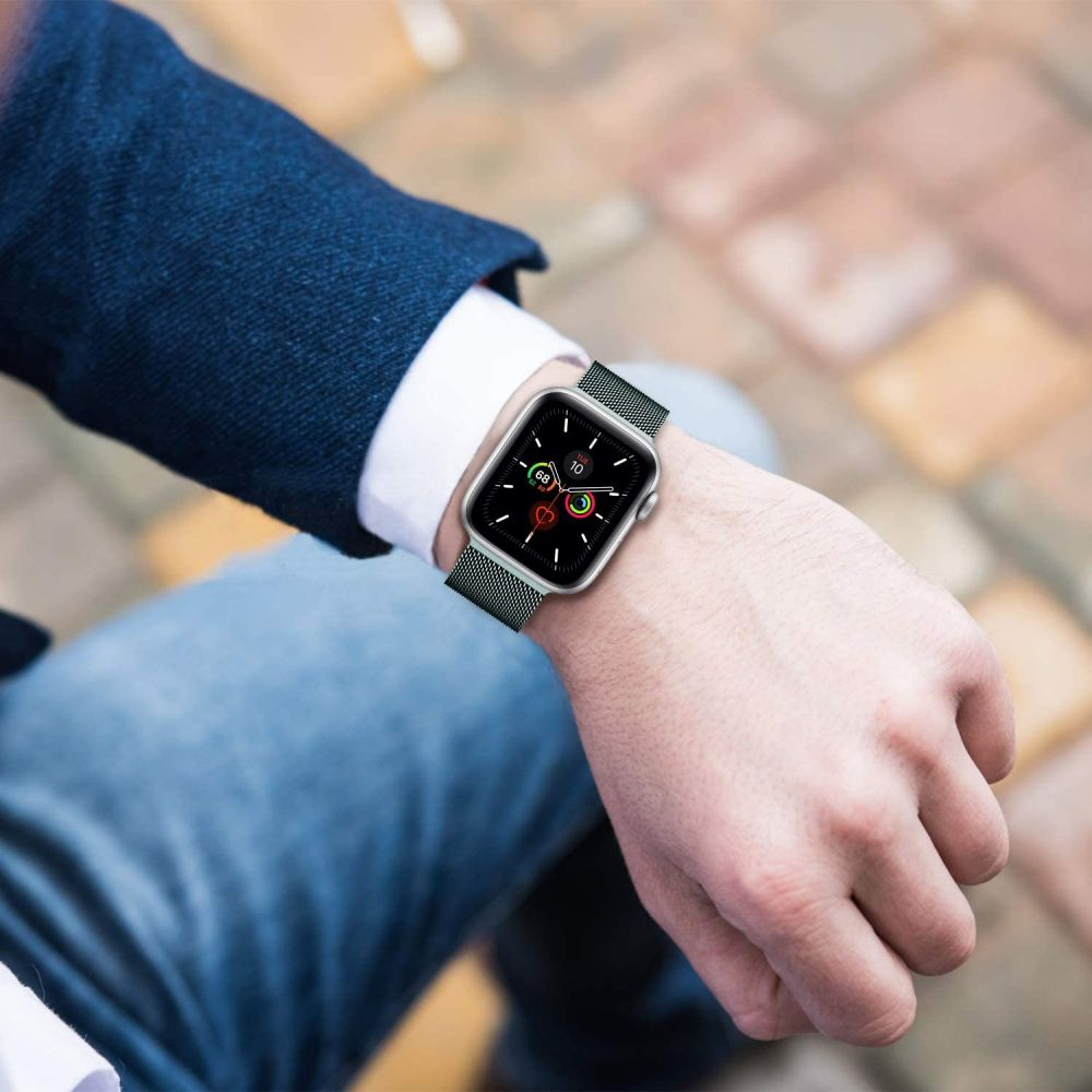 Eine Person trägt eine silberne Smartwatch mit einem dunkelgrünen Netzarmband am Handgelenk.