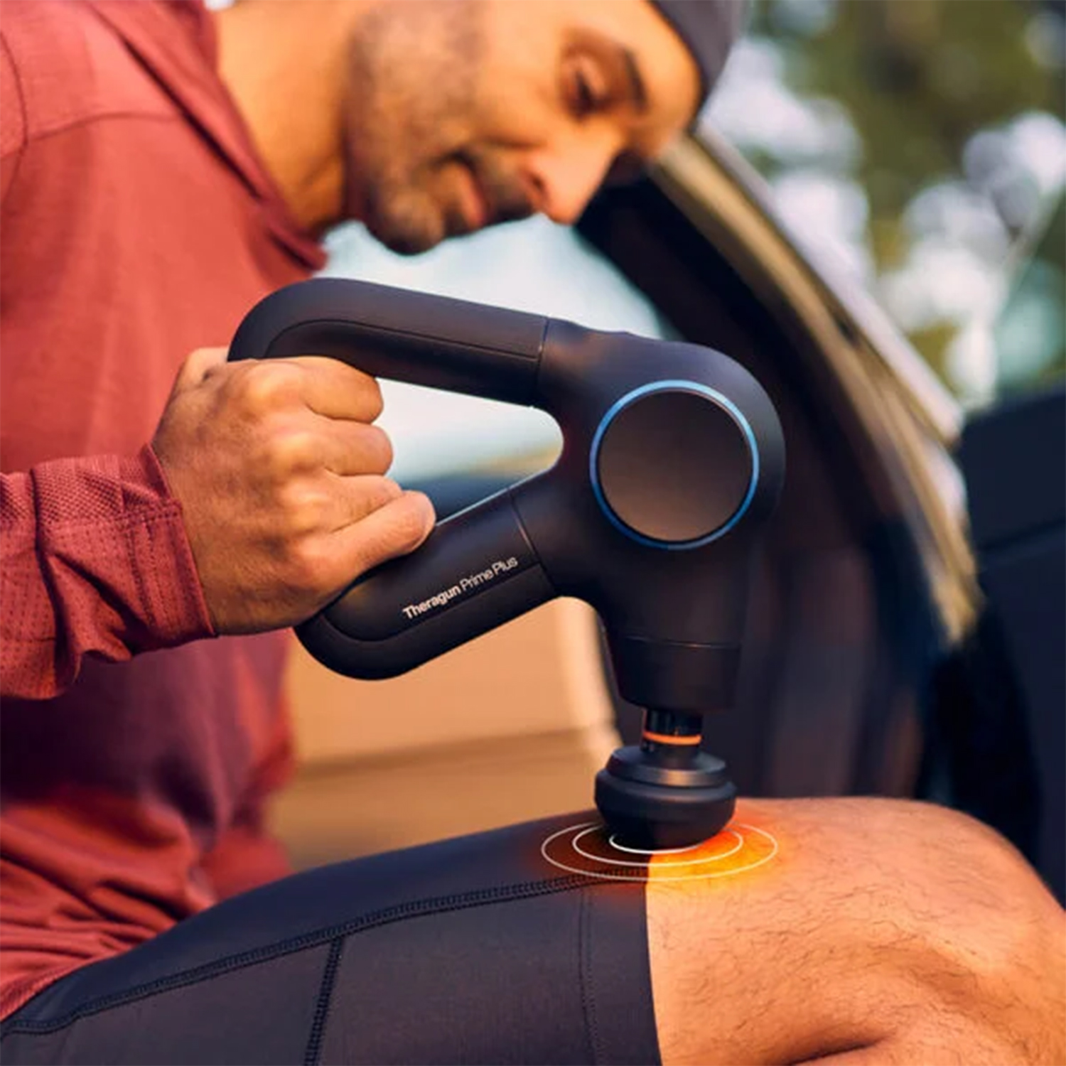 Mężczyzna używa pistoletu do masażu na kolanie.