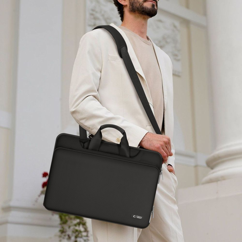 Mann mit weißem Anzug trägt schwarze Laptoptasche über der Schulter.