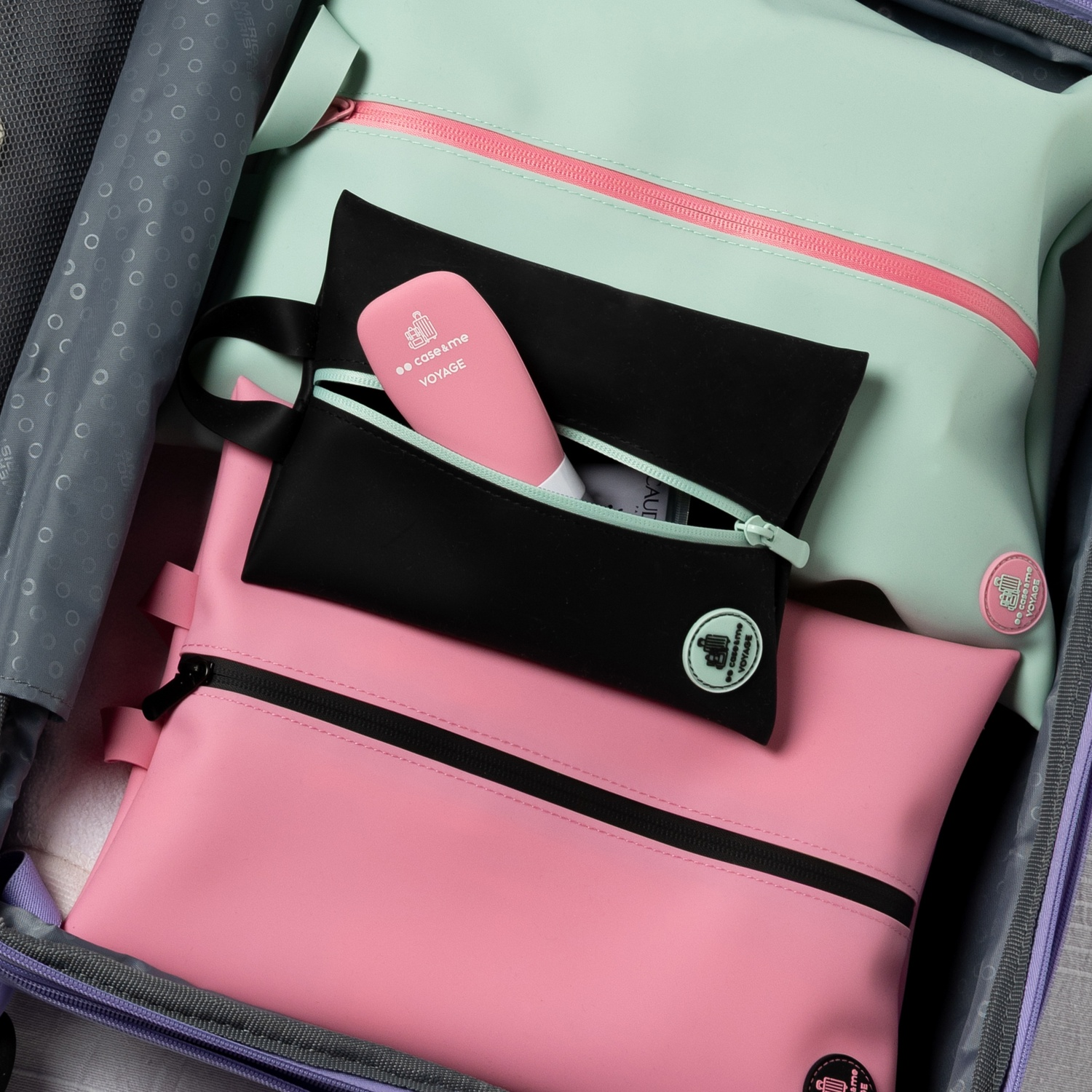 Una bolsa de aseo rosa y verde menta con una botella rosa dentro de un neceser negro.