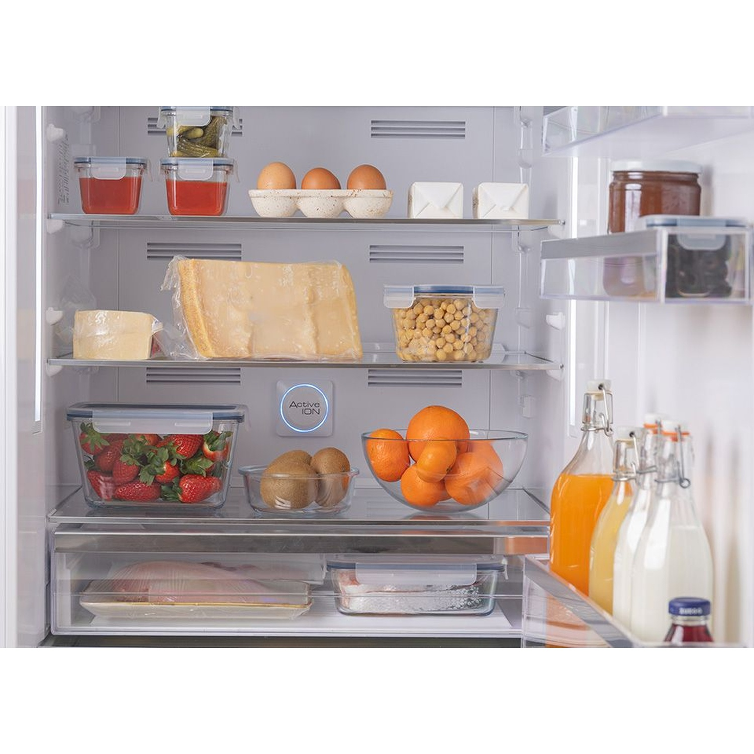 Refrigerador lleno de comida: bayas, naranjas, huevos, queso, bebidas.