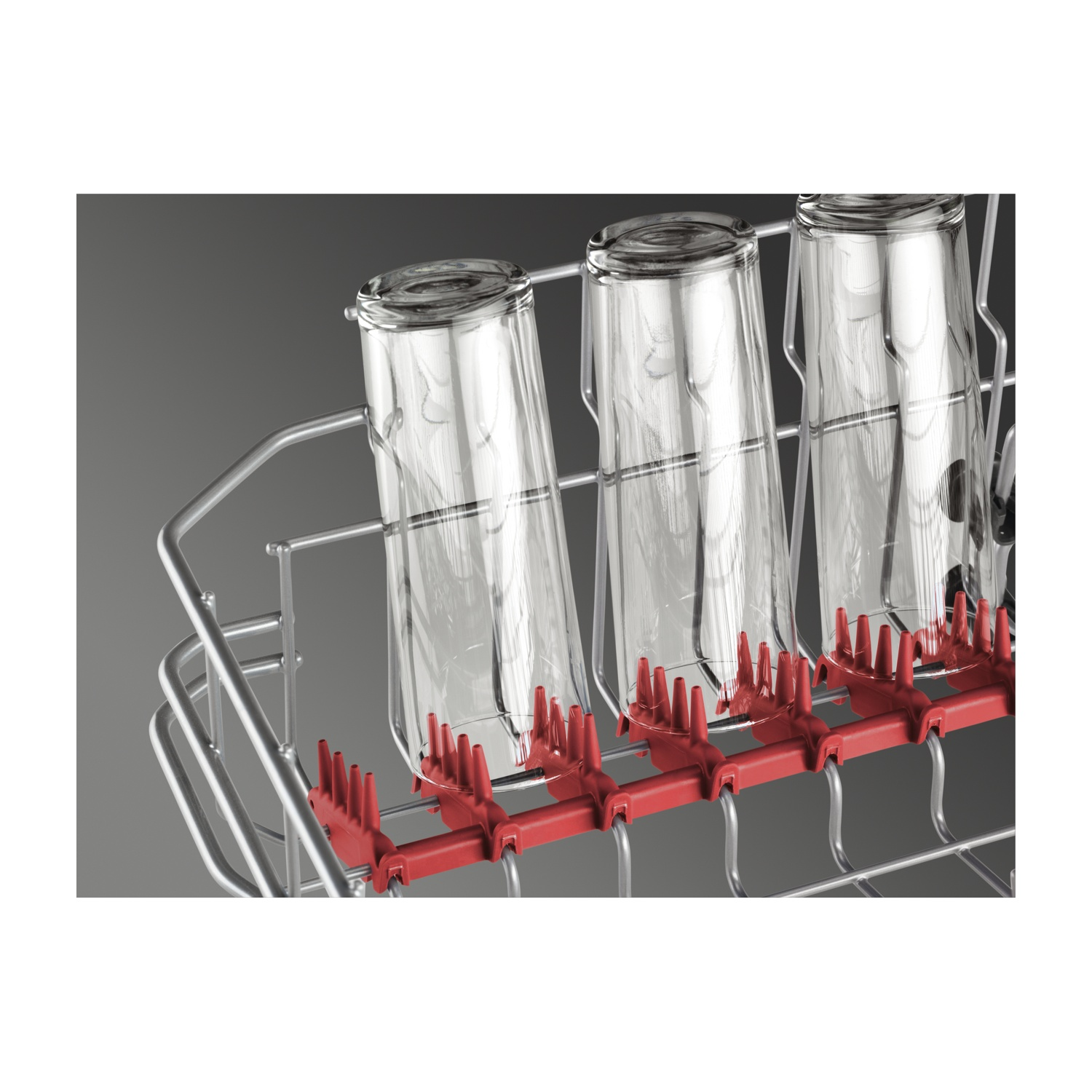 Tres vasos transparentes de pie en una rejilla de lavavajillas con soportes rojos.