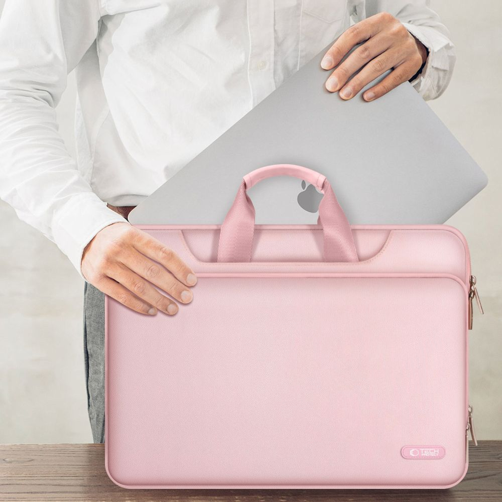 Eine Person legt einen silbernen Laptop in eine rosafarbene Laptoptasche.
