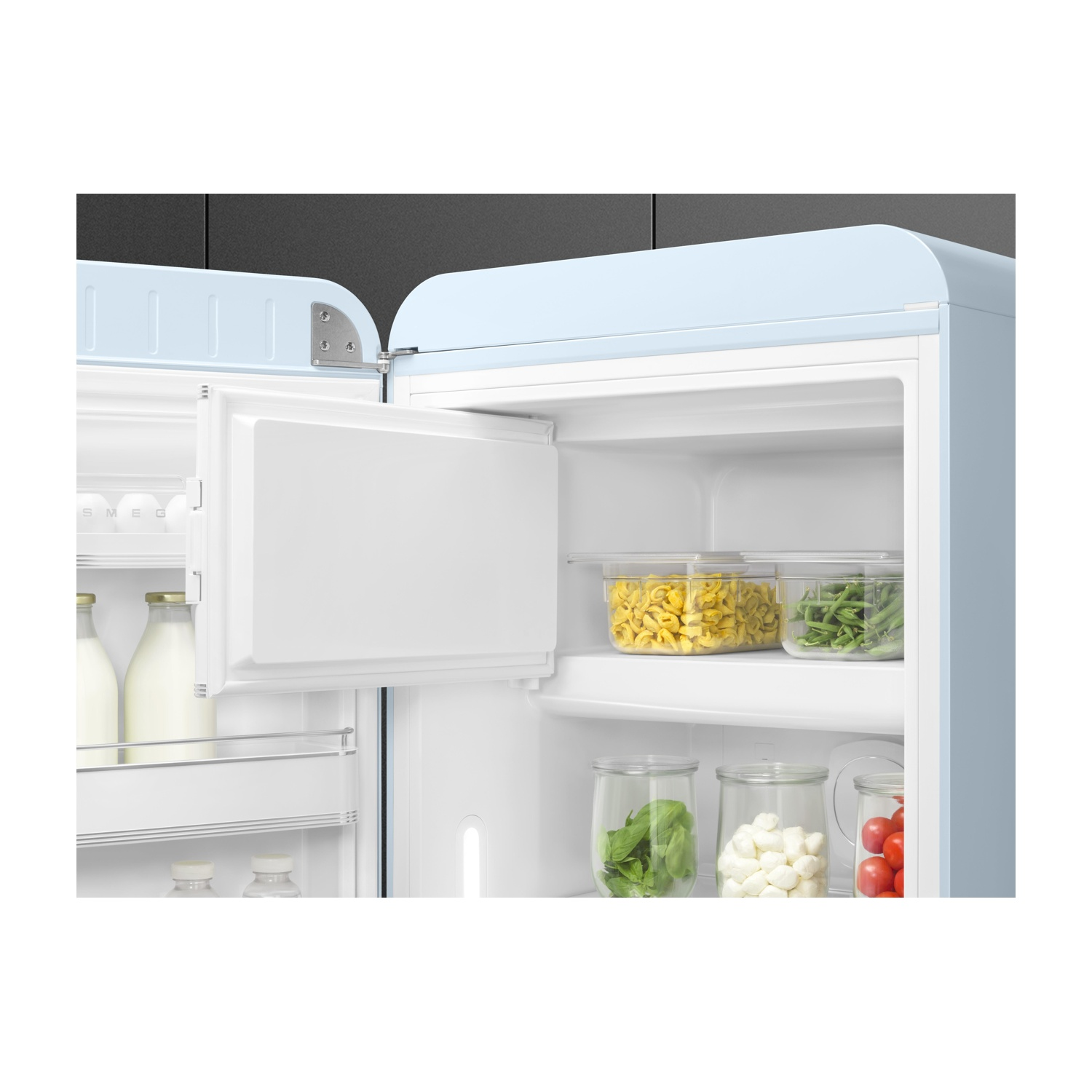 Un refrigerador azul claro abierto con leche, pasta, judías verdes, espinacas, mozzarella y tomates.