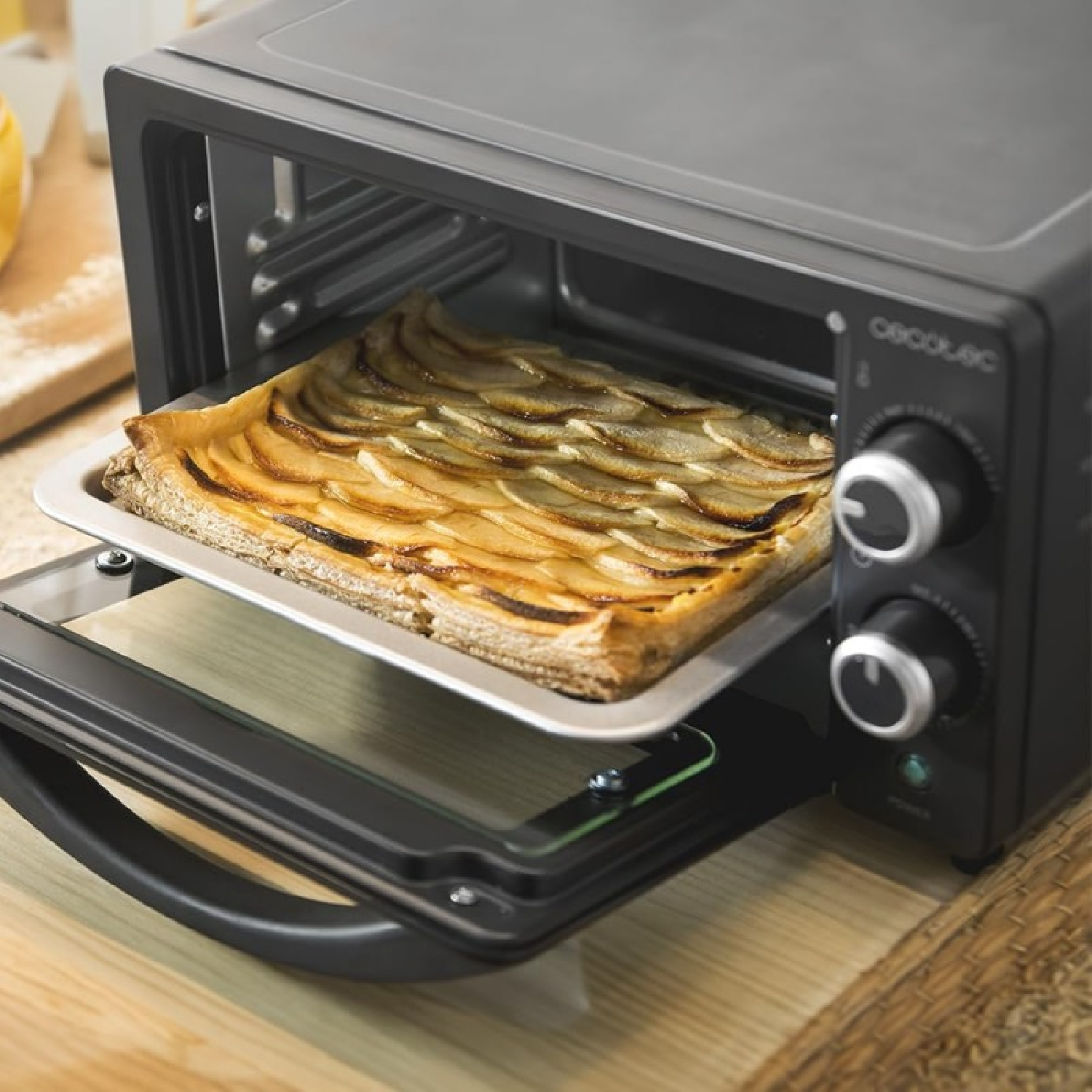 Una tarta de manzana rectangular en una bandeja de horno dentro de un horno pequeño.