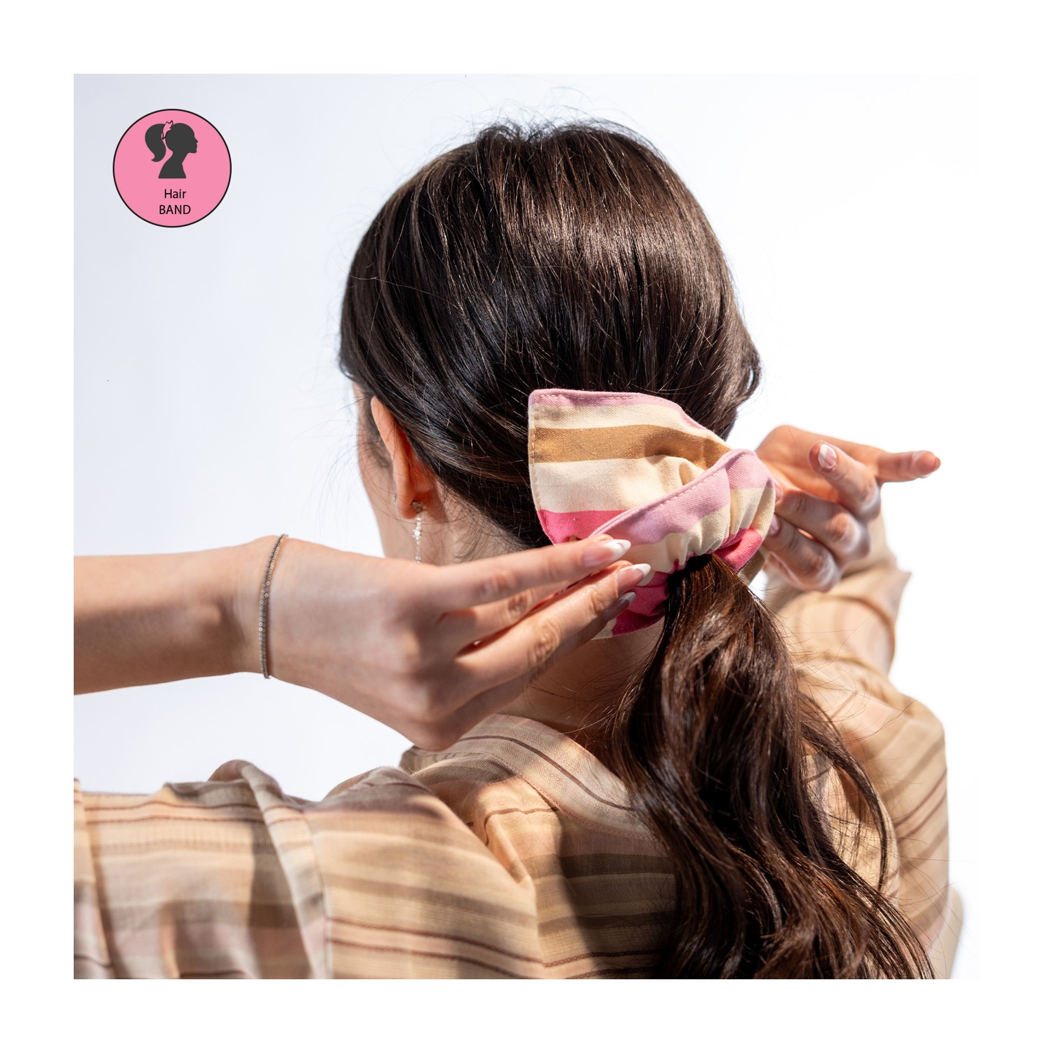 Donna si lega i capelli castani con un elastico a righe. Logo fascia.