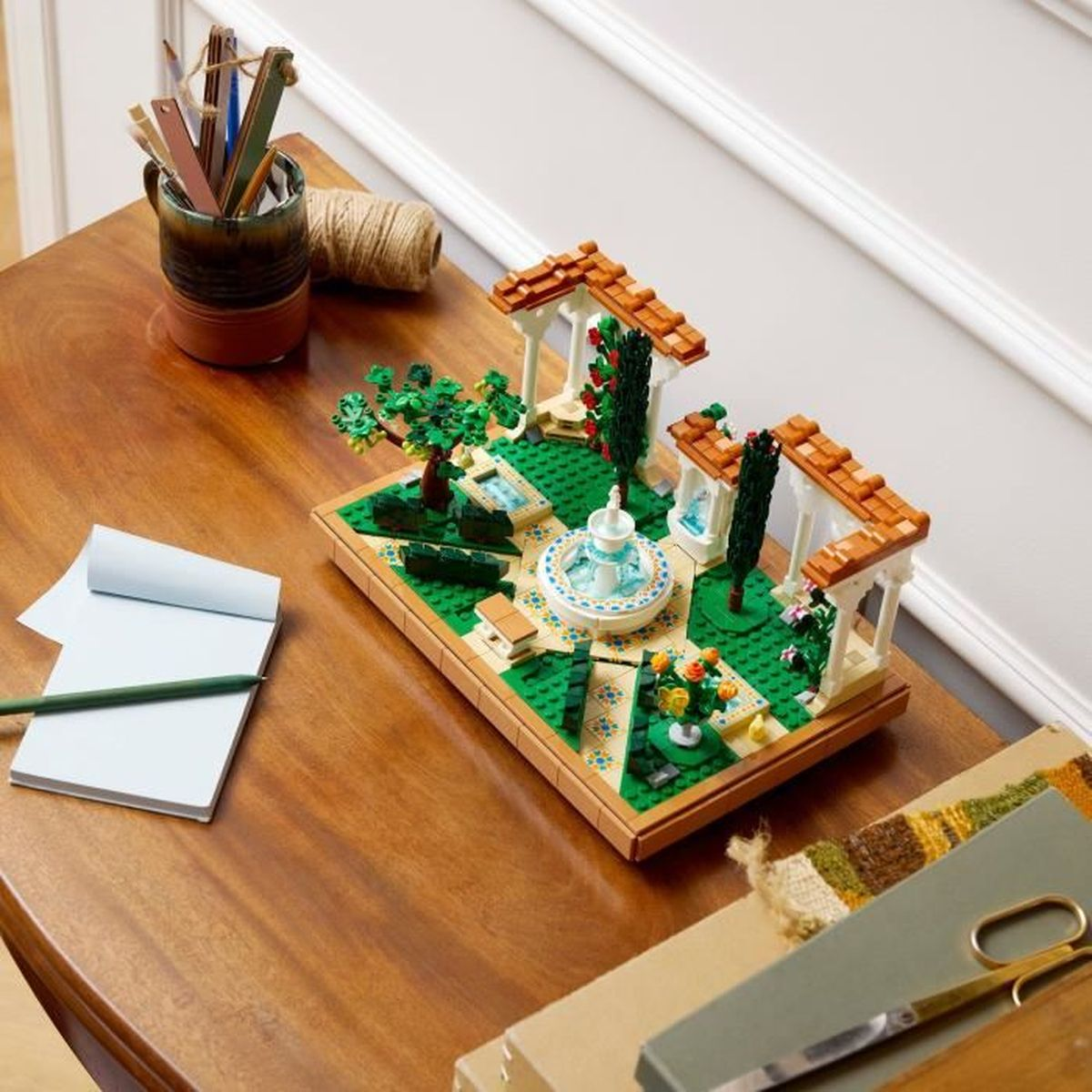 Een Lego-model van een tuin met fontein, bomen en prieeltjes.