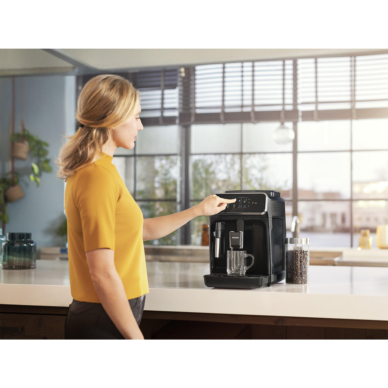 Mujer operando máquina de café con taza y frasco.