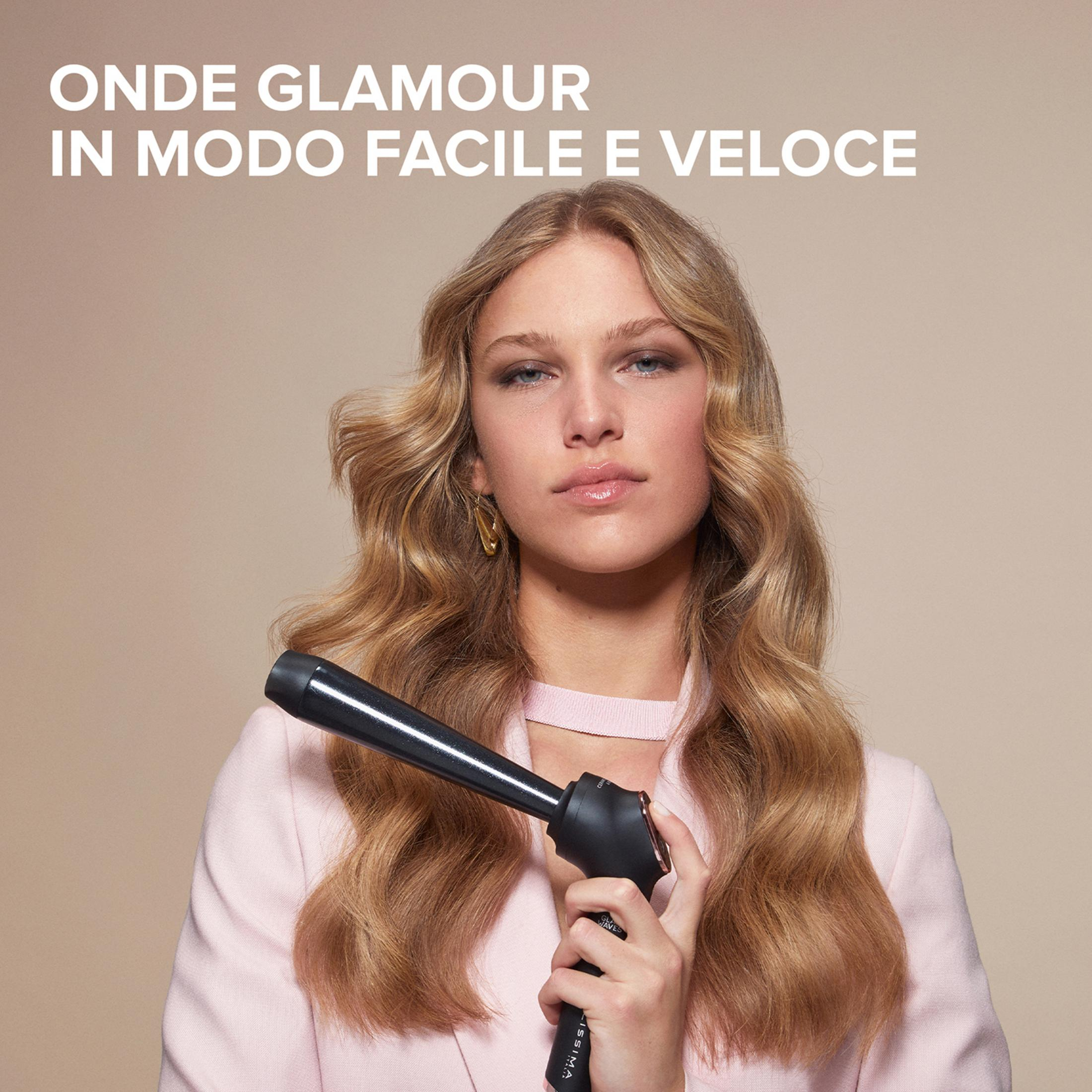 Una donna con lunghi capelli biondi mossi tiene in mano un arricciacapelli nero.