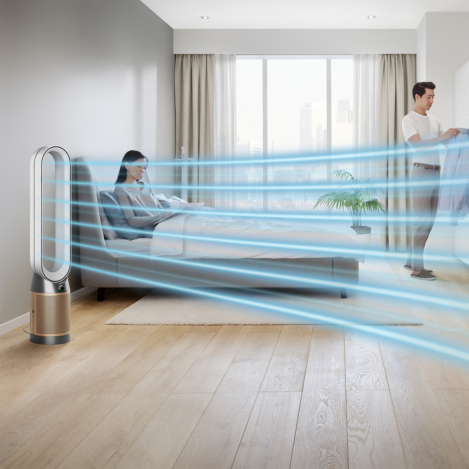 Ein Luftreiniger bläst blaue Luftströme in ein Schlafzimmer, wo eine Frau liest und ein Mann Kleidung sortiert.