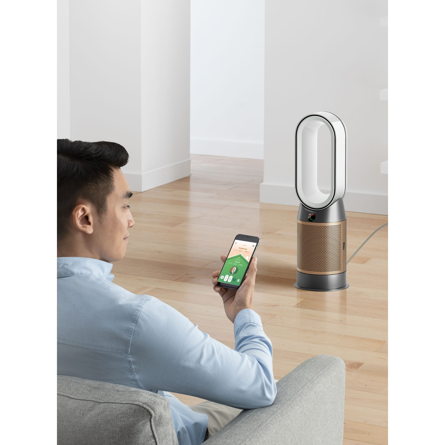 Uomo su divano usa purificatore Dyson tramite app su telefono.