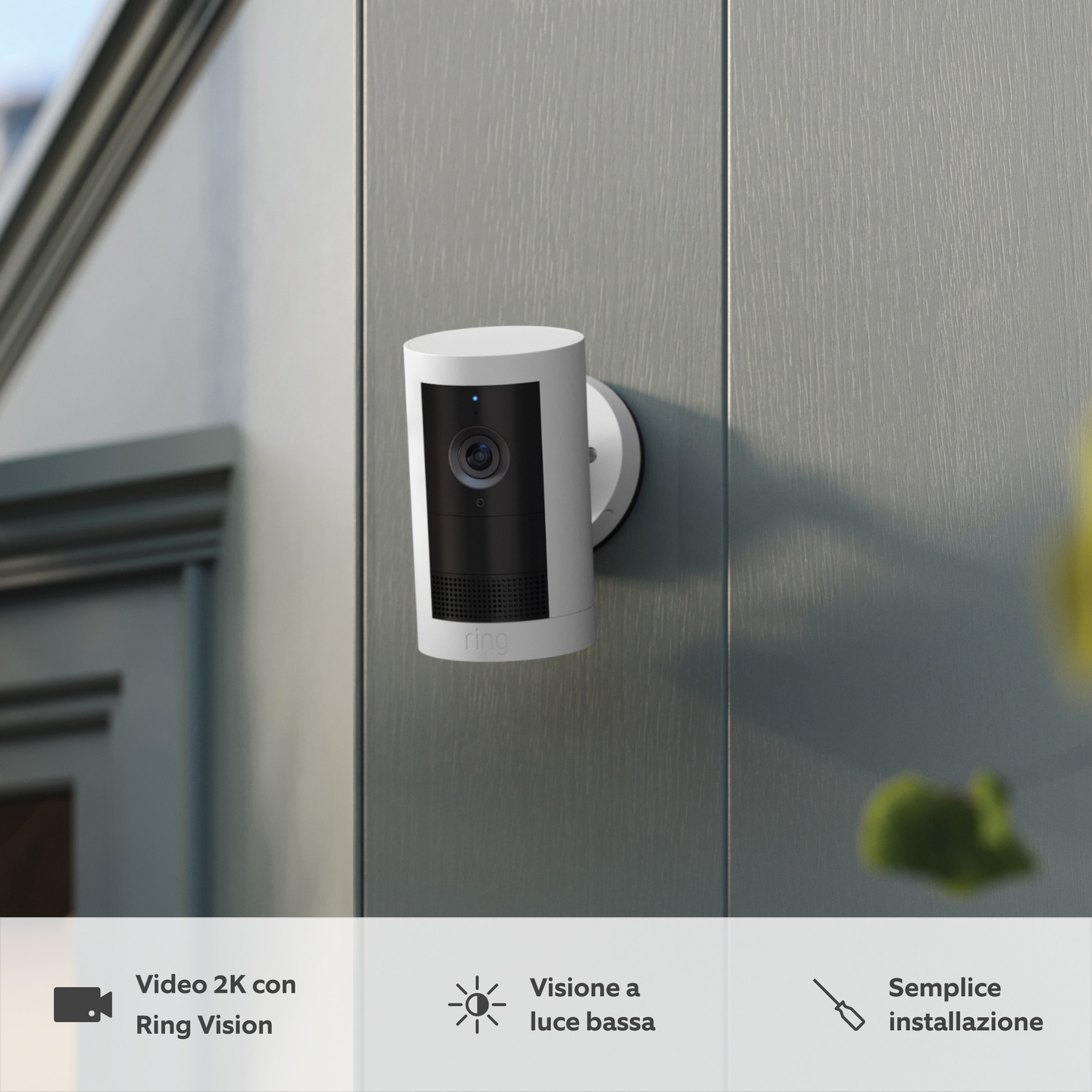 Biała kamera Ring zamontowana na szarej ścianie, z niebieską diodą.