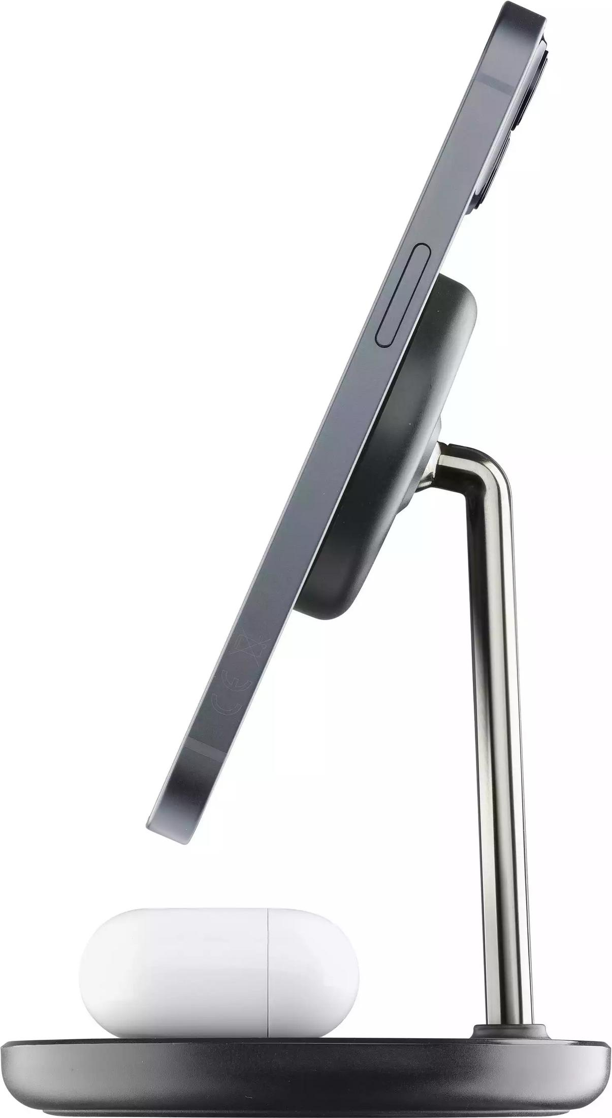 Ein graues Smartphone lädt auf einem Ständer, daneben liegen weiße Kopfhörer.