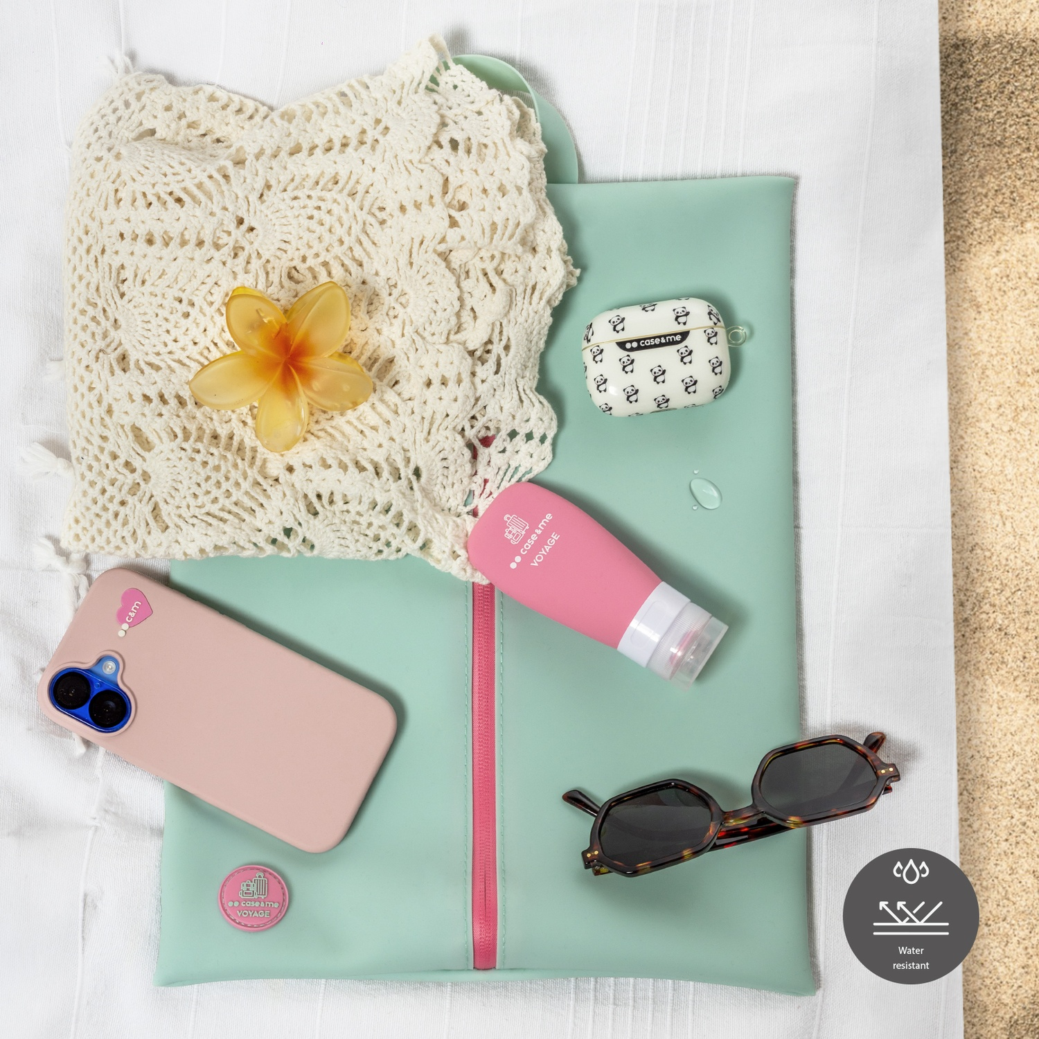 Un teléfono rosa, gafas de sol, flor y tubo cosmético sobre fondo verde menta.