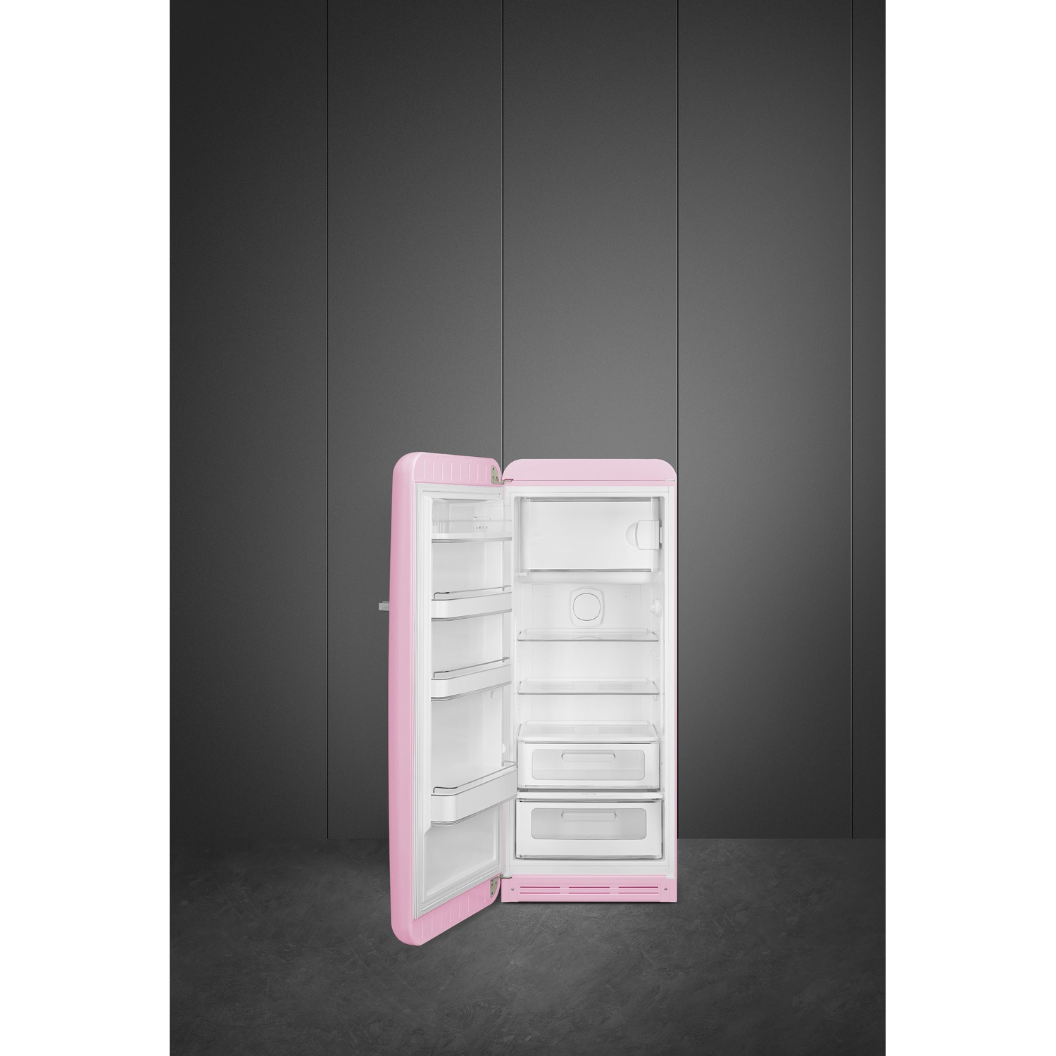 Un frigorifero rosa con porta aperta su pavimento scuro e muro grigio.