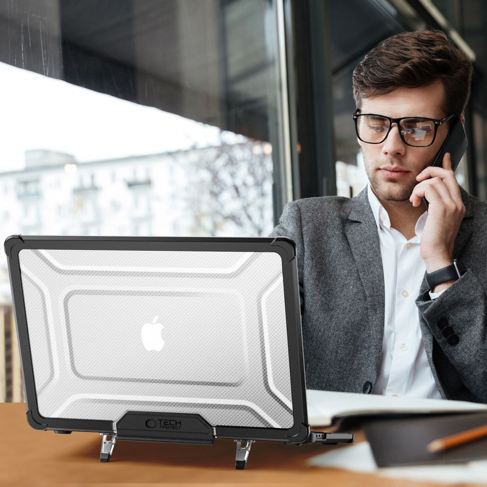 Mann im Anzug telefoniert und schaut auf Laptop mit Schutzhülle.