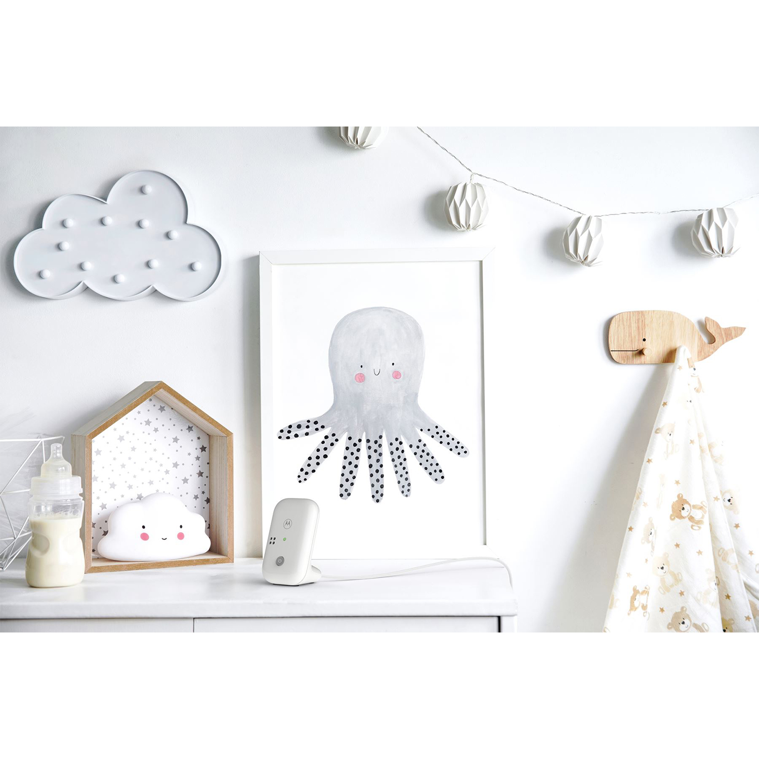 Ein Kinderregal mit Babyflasche, Wolkenlampe, Oktopus-Kunst und Walhaken.