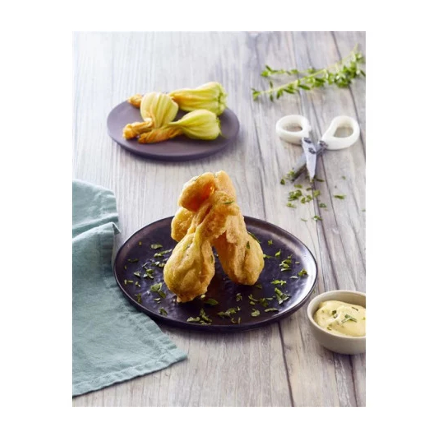Fiori di zucca fritti su piatto con salsa e erbe.