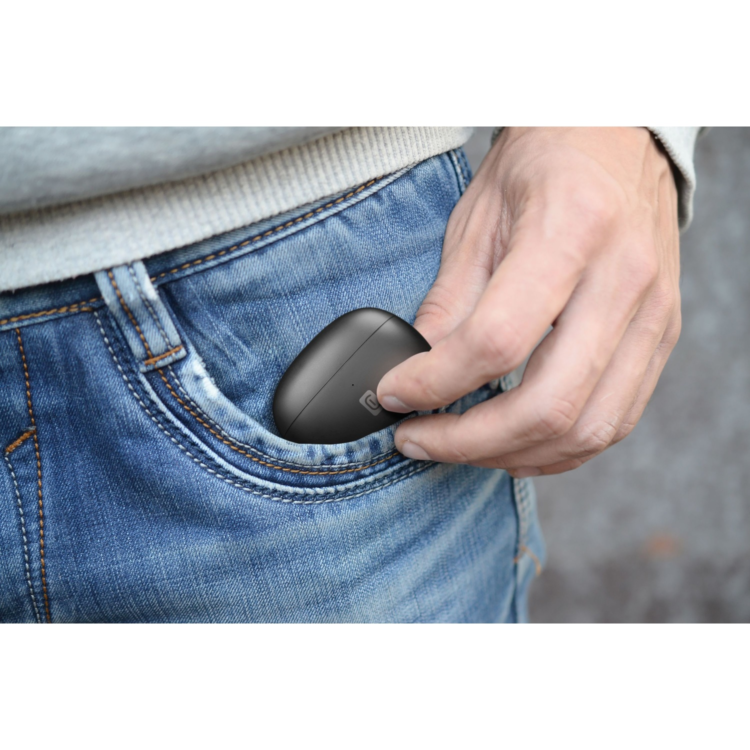 Eine Hand legt schwarze Kopfhörer in eine Jeans-Tasche.