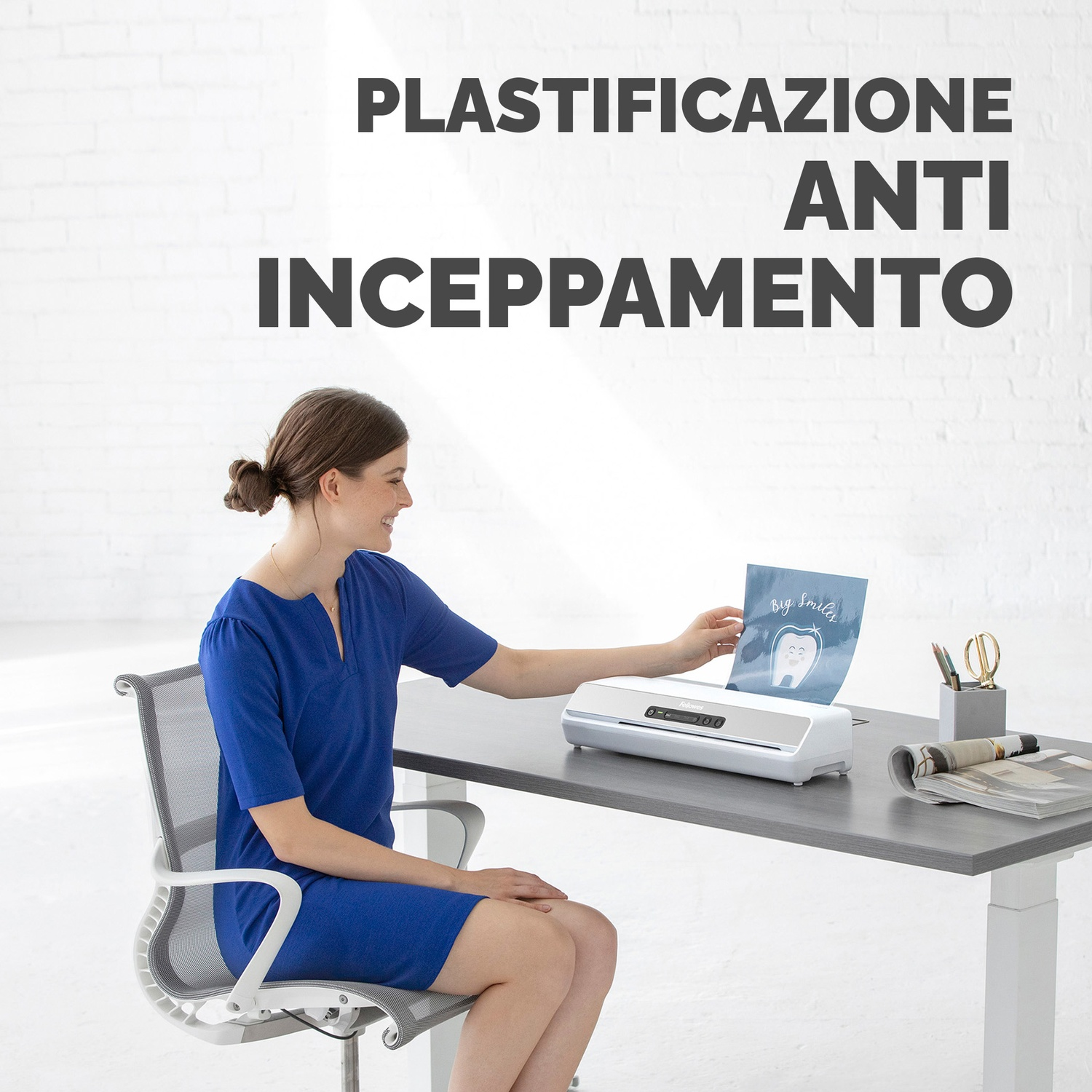 Una donna in abito blu usa una plastificatrice con un foglio raffigurante un dente.